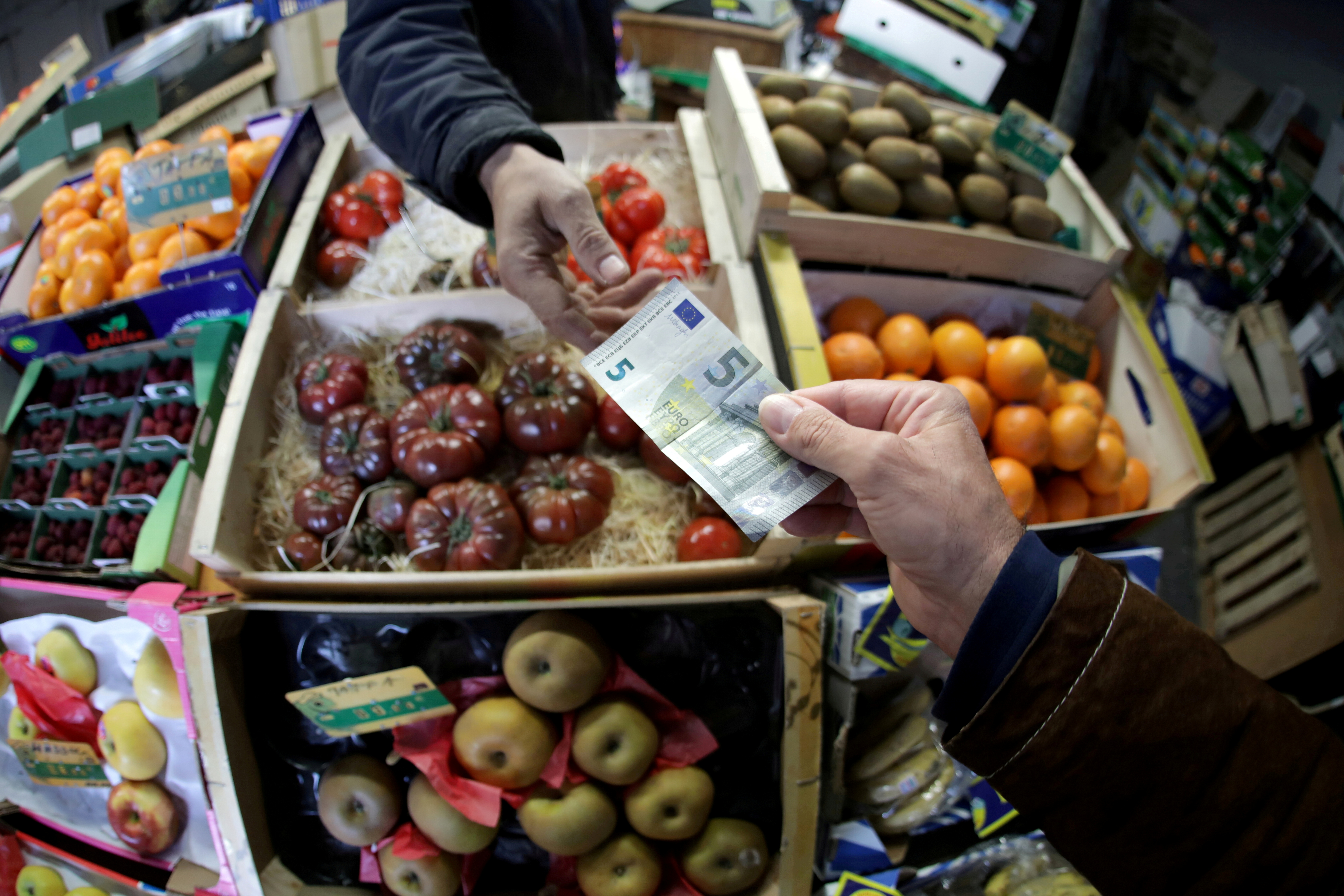 A shopper pays with a Euro bank note in a market in Nice