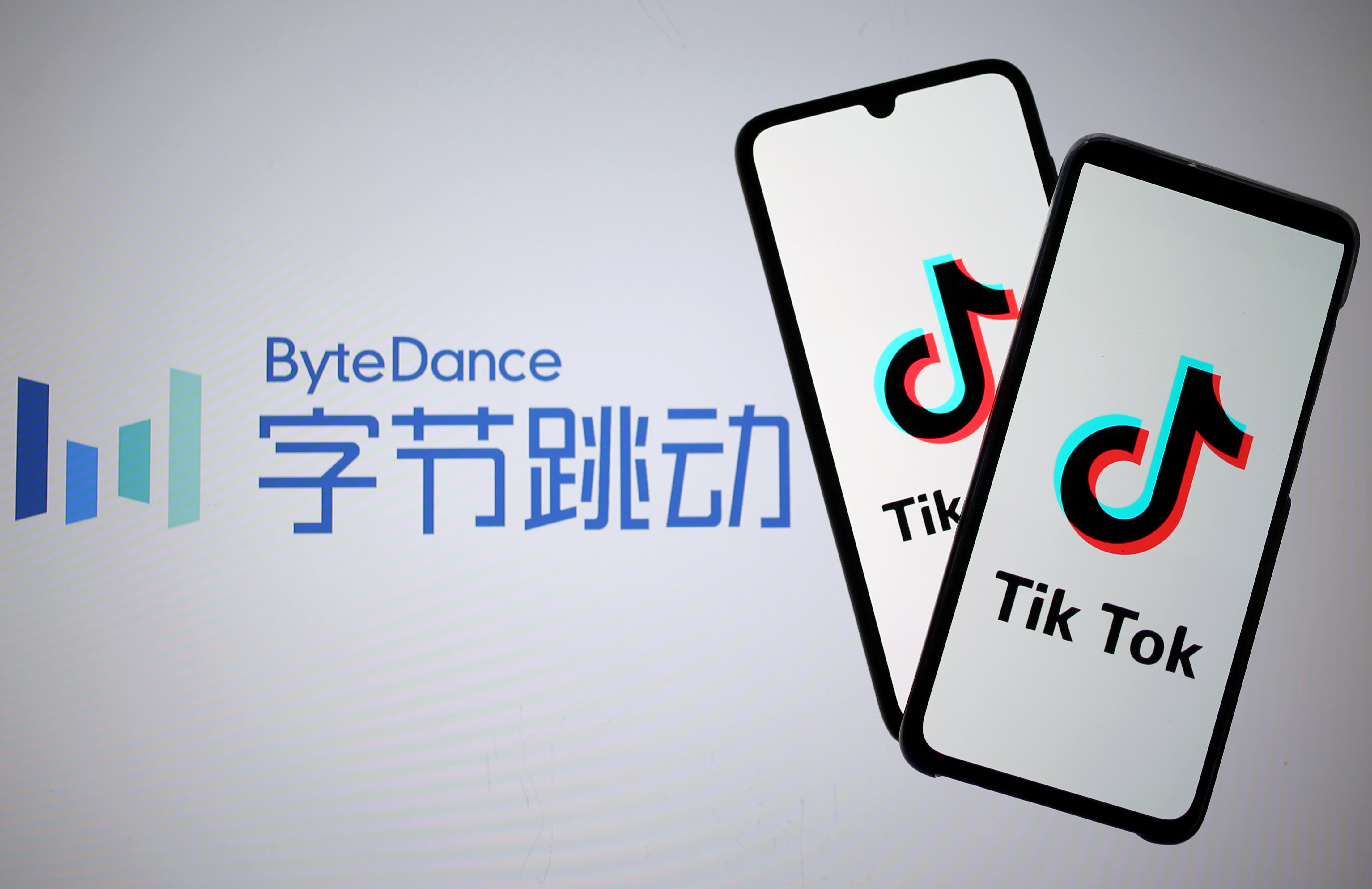Tik Tok logos are seen on smartphones in front of displayed ByteDance logo in this illustration