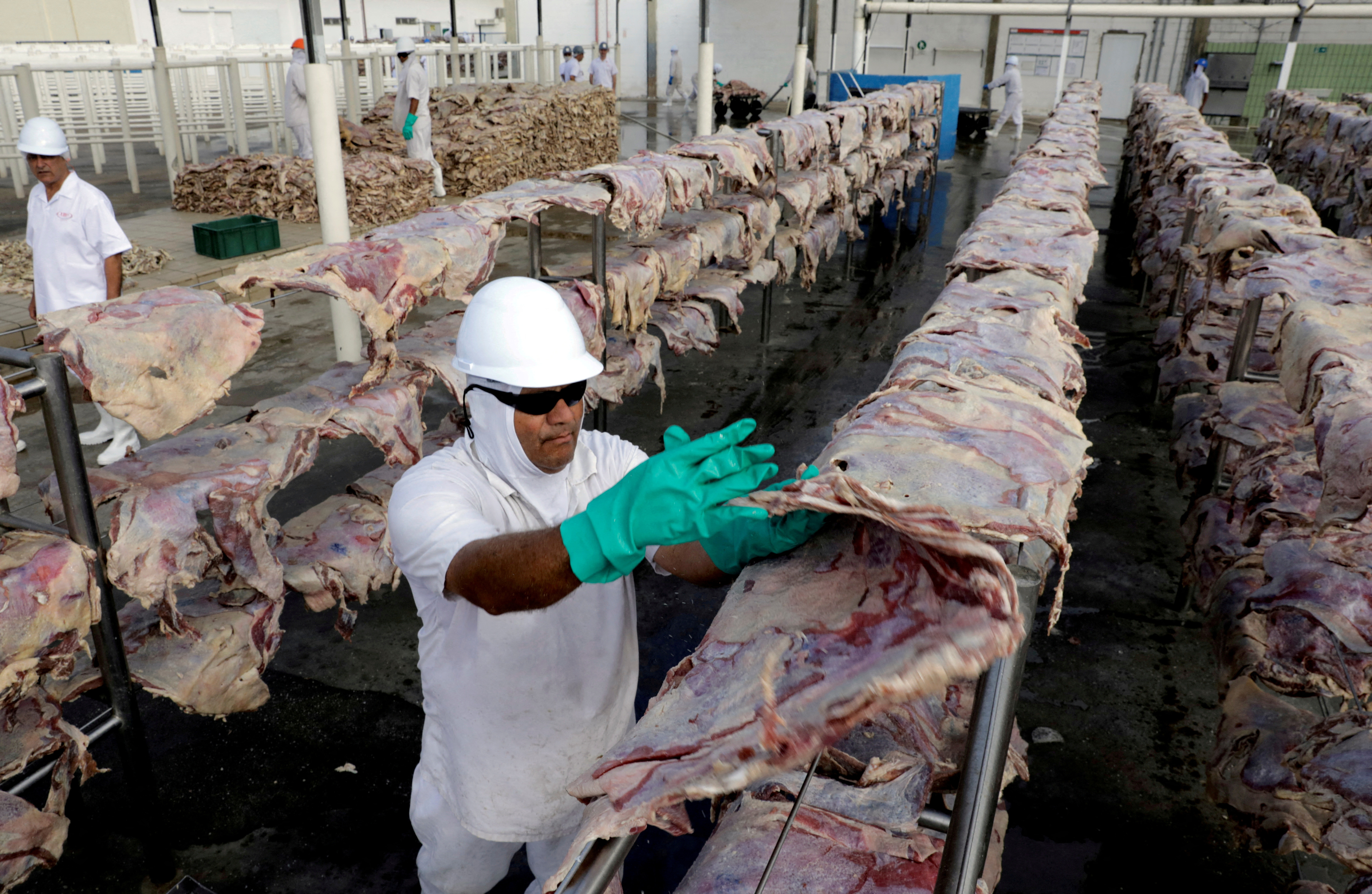 Un trabajador unta carne salada que será secada y luego empacada en una planta de JBS SA, la mayor productora de carne bovina del mundo, en Santana de Parnaiba.