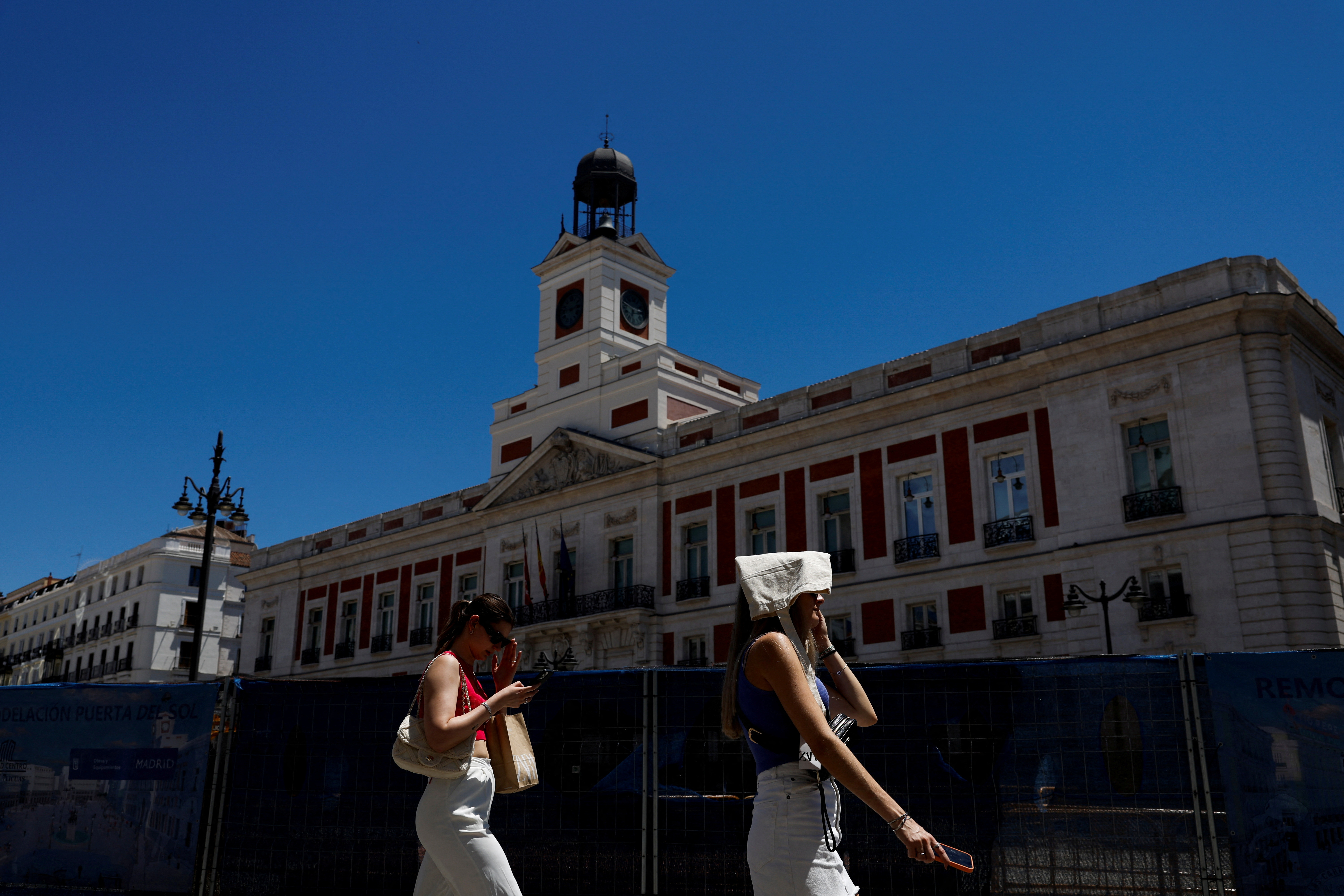 A woman covers her head with a bag during a hot day as Spain braces for a heatwave in Madrid