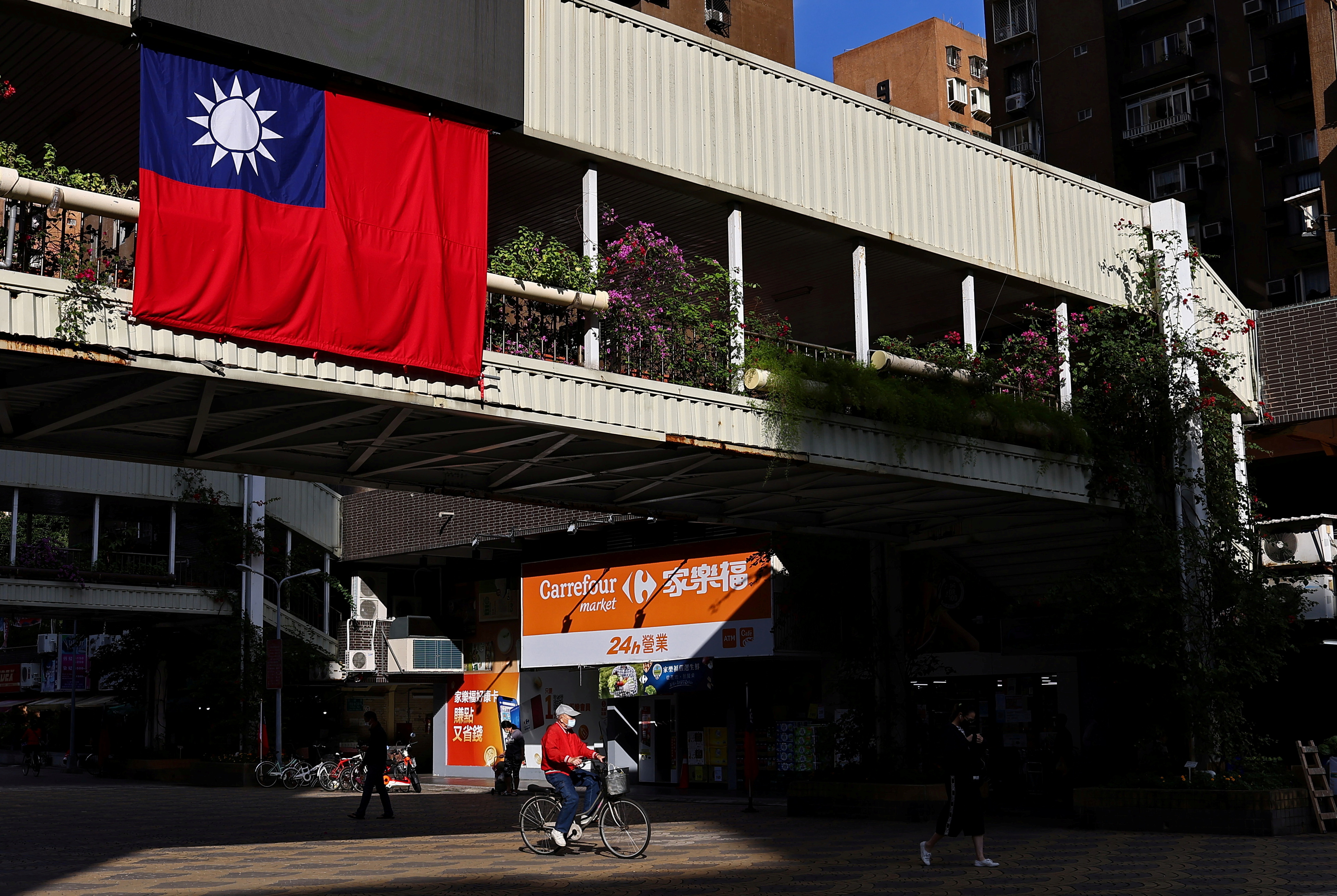 A man cycles past a Taiwan flag in Taipei