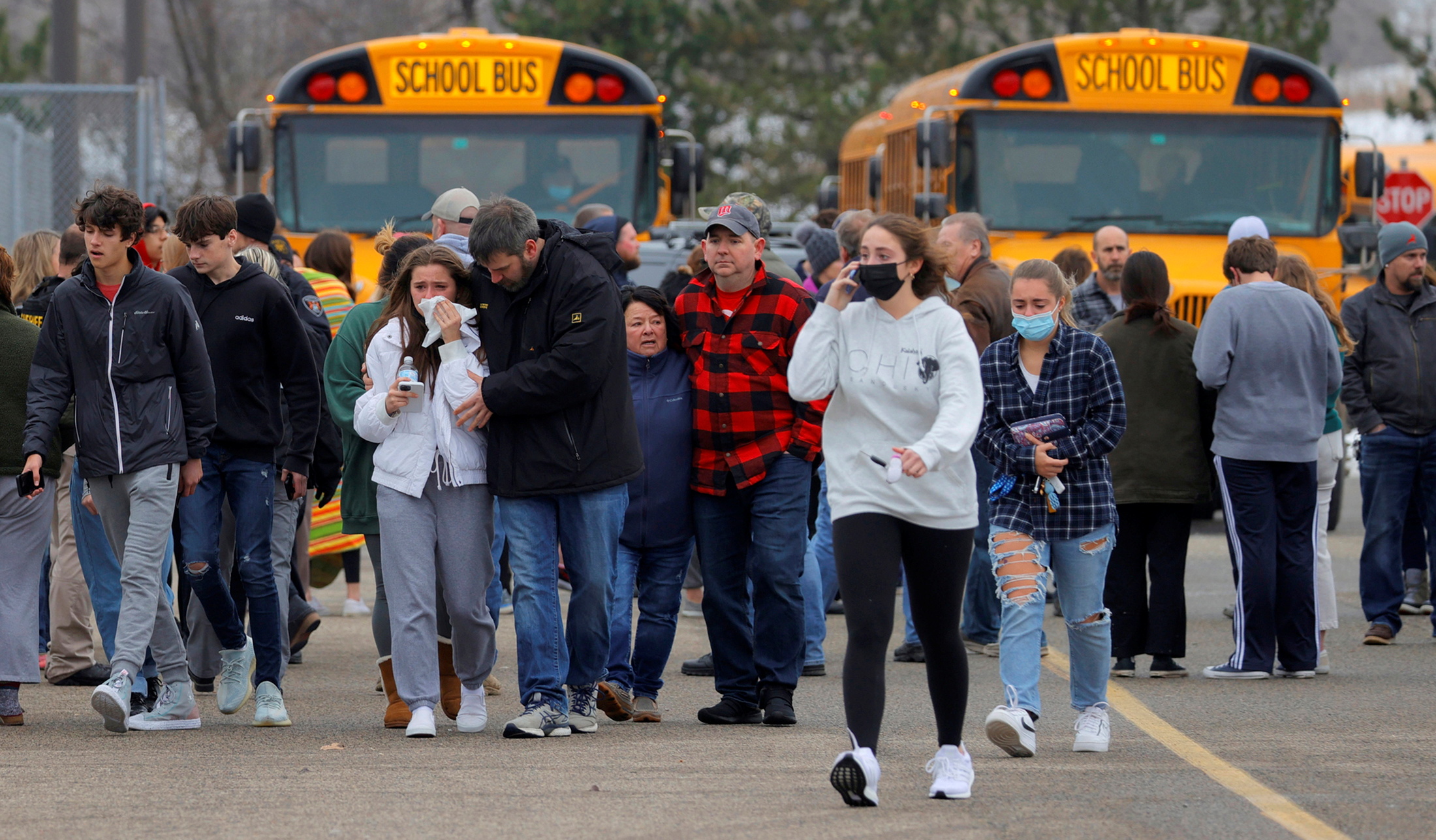 Parents walk away with their kids from the Meijer's parking lot where many students gathered following an active shooter situation at Oxford High School in Oxford, Michigan, U.S. November 30, 2021.  Eric Seals-USA TODAY NETWORK via REUTERS 