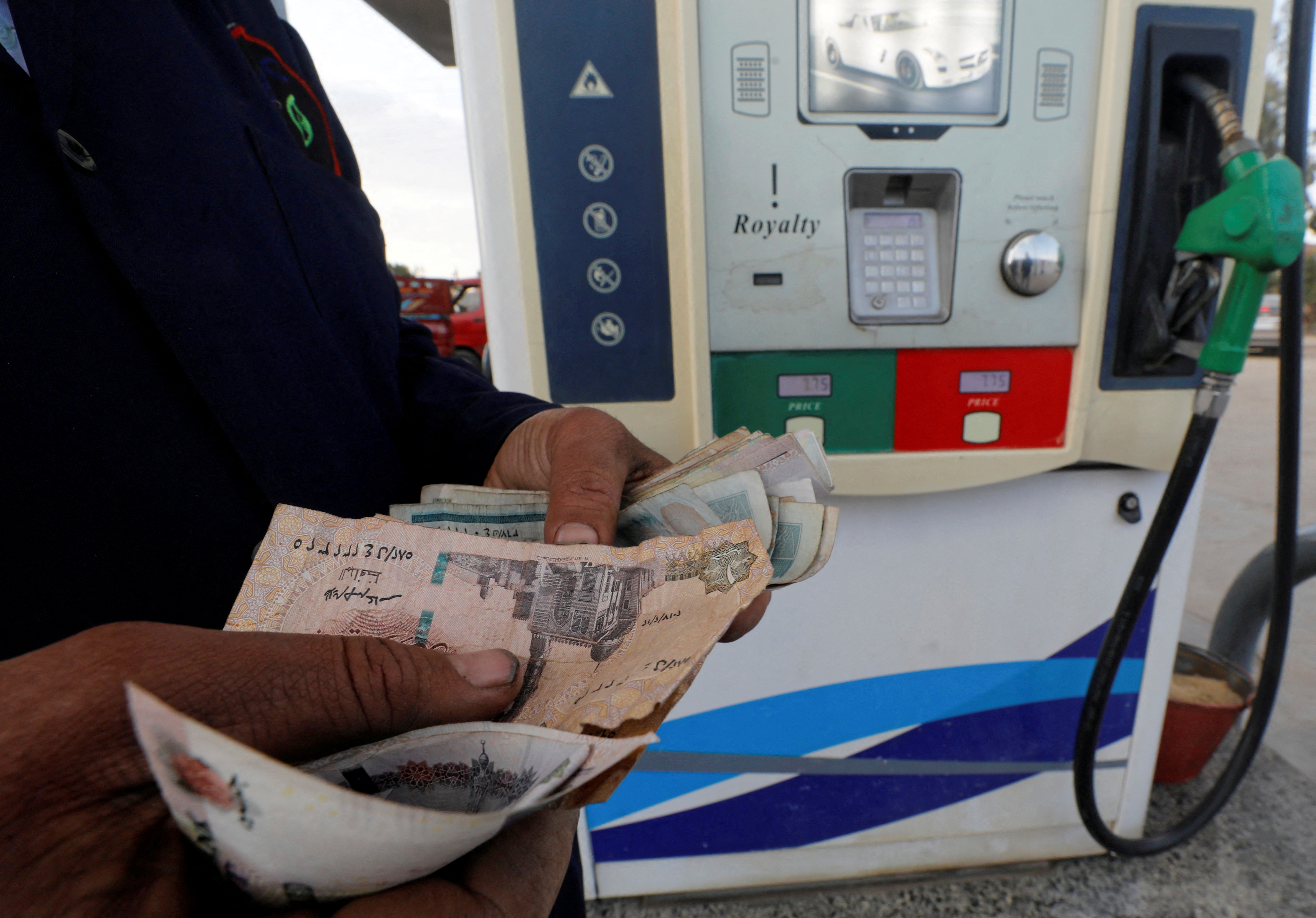 A worker counts money at a CO-OP petrol station in Cairo