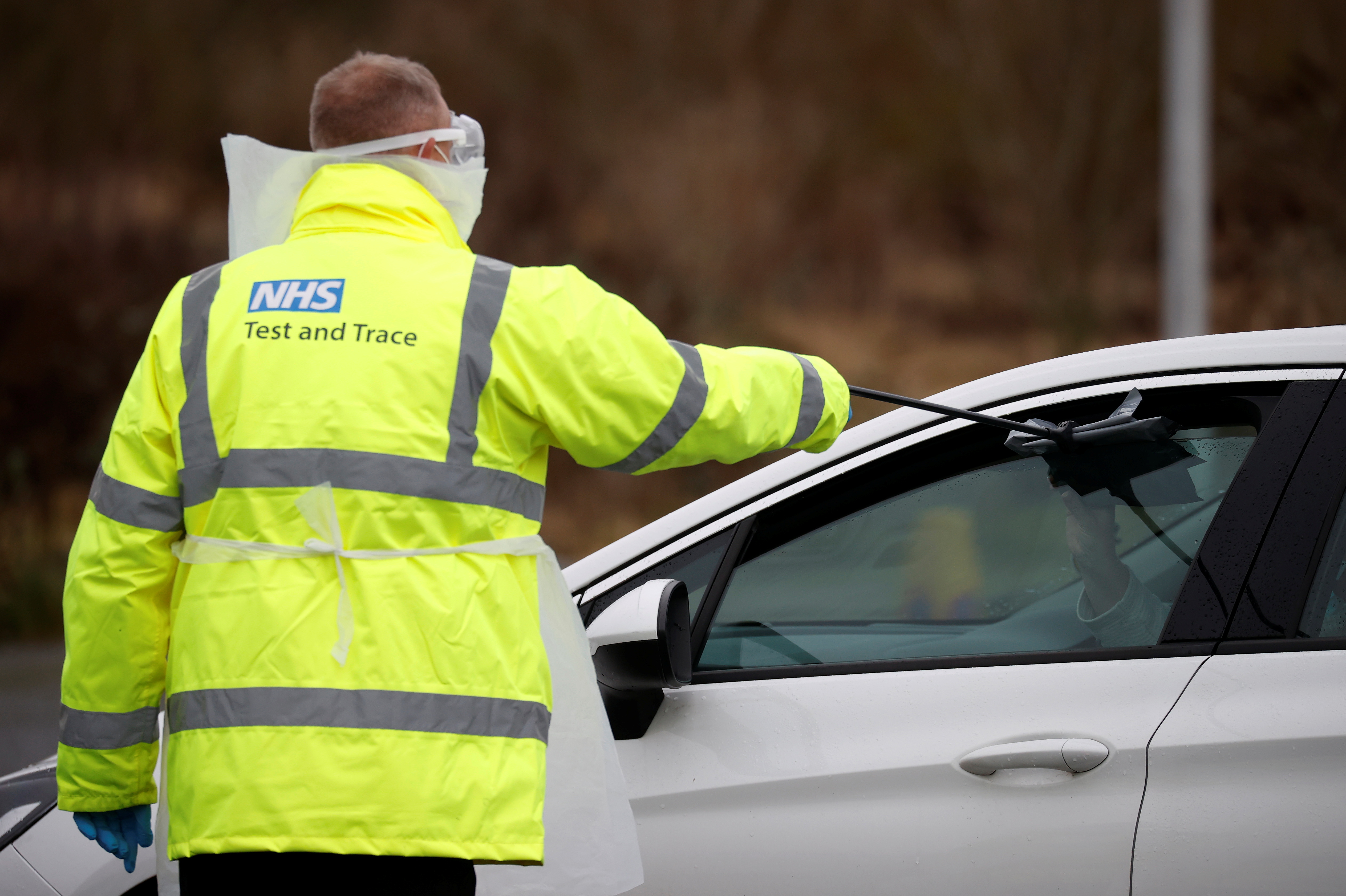 A member of NHS Test and Trace staff gives people a testing kit as they arrive at a mobile testing centre amid the outbreak of the coronavirus disease (COVID-19) in Southport, Britain, February 3, 2021. REUTERS/Phil Noble