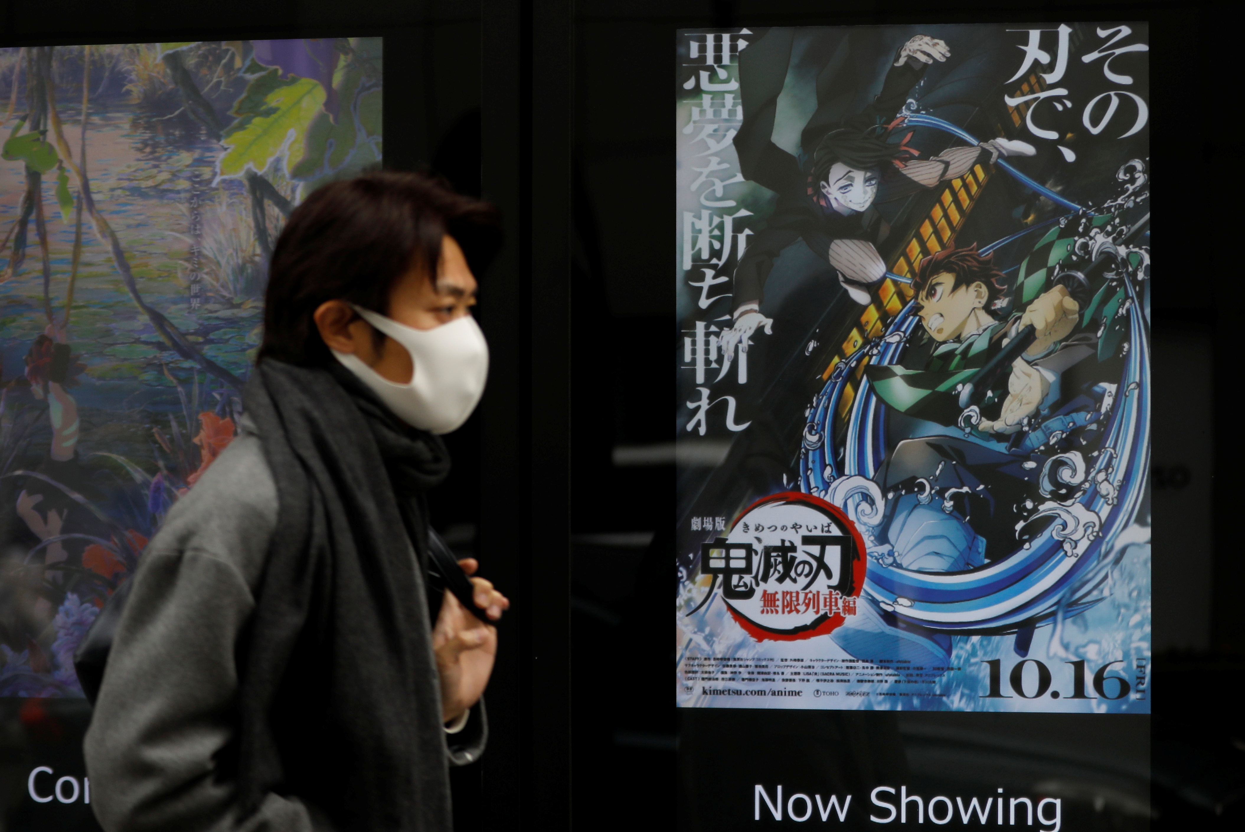 A man wearing a protective mask amid the coronavirus disease (COVID-19) outbreak walks past a poster for an animated movie 