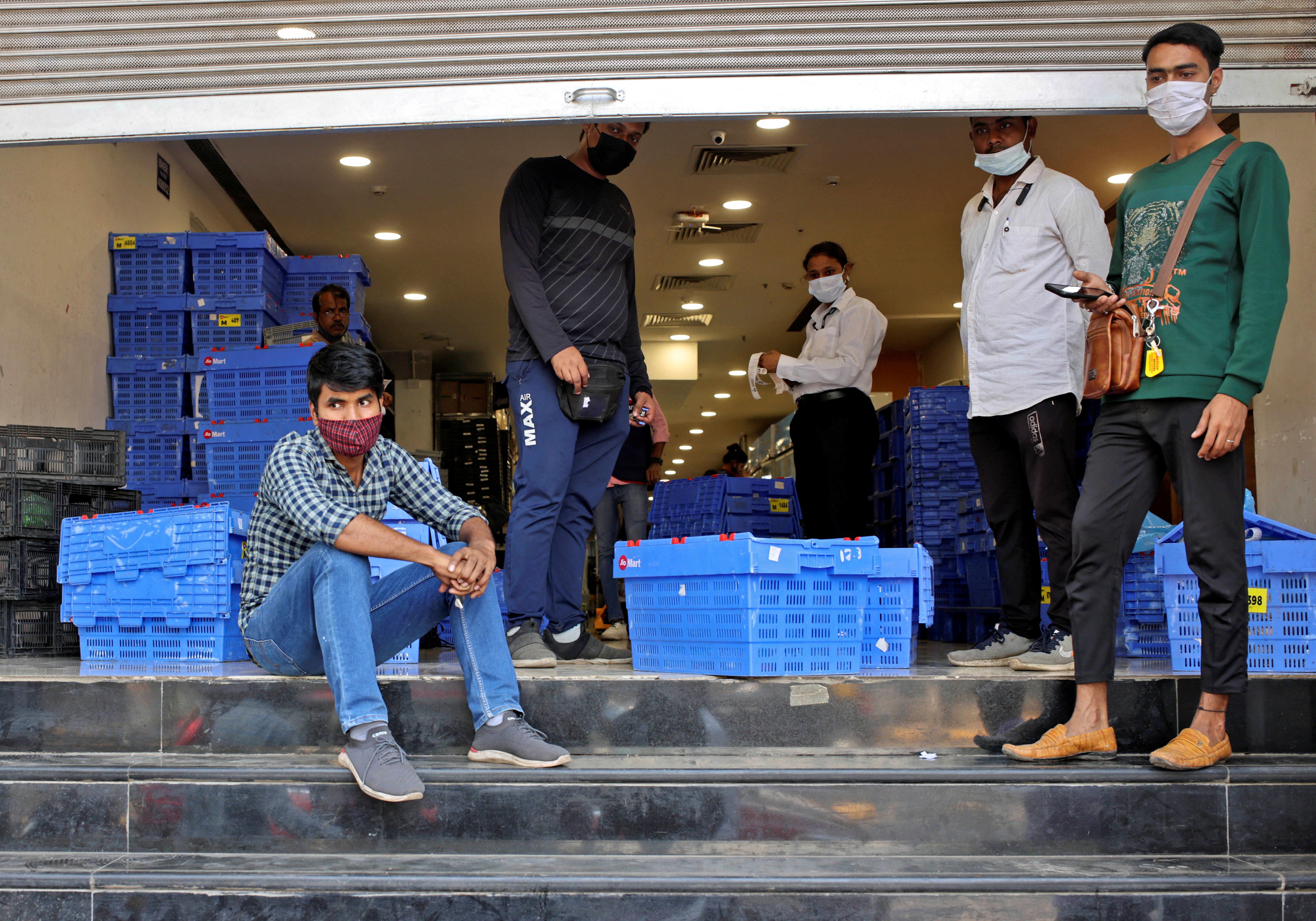 Workers from Reliance's JioMart take a break as they stock their products inside a Future Retail's closed Big Bazaar retail store in Mumbai