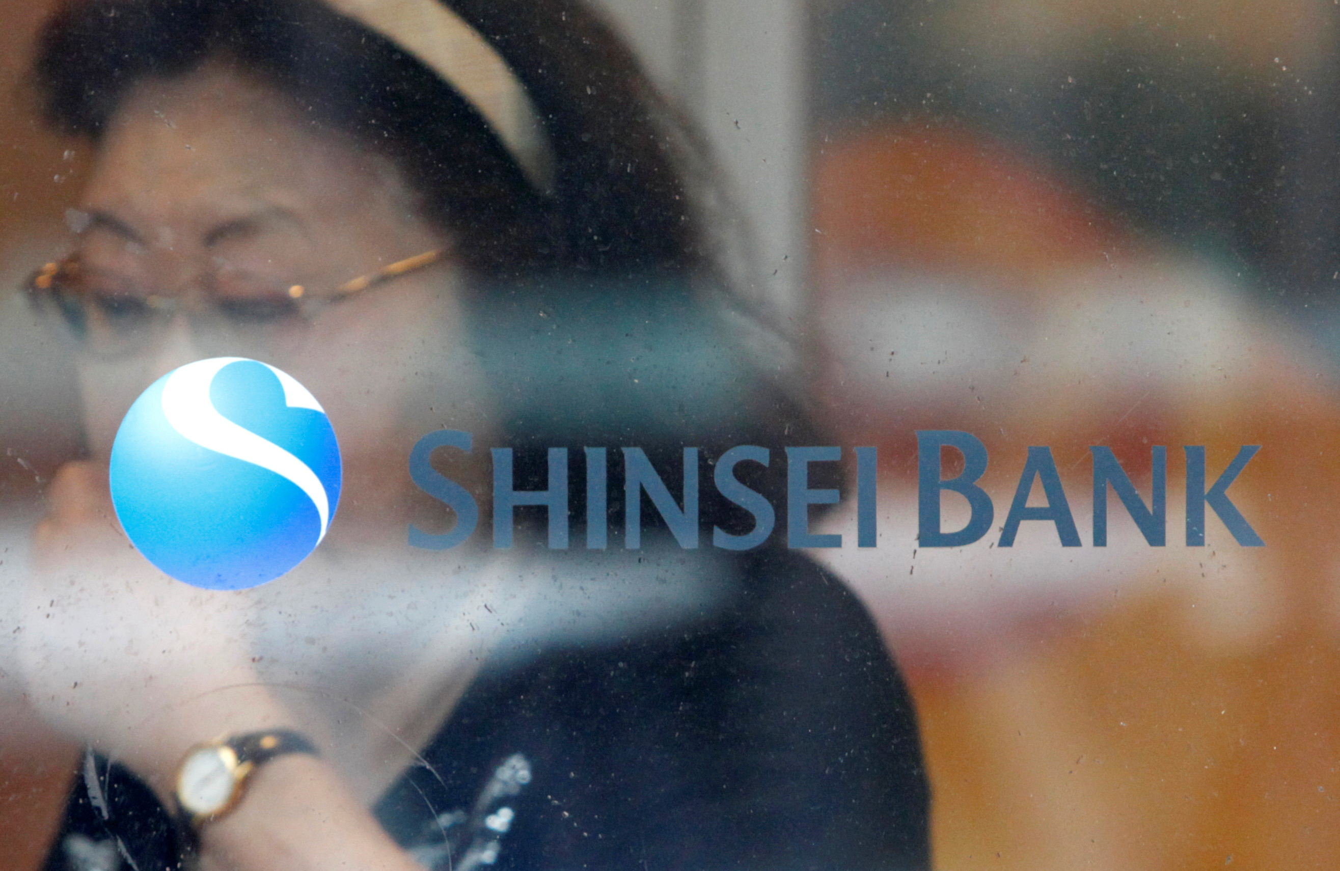 A woman walks past a logo of the Shinsei Bank at its branch in Yokohama, south of Tokyo, June 23, 2010. REUTERS/Issei Kato