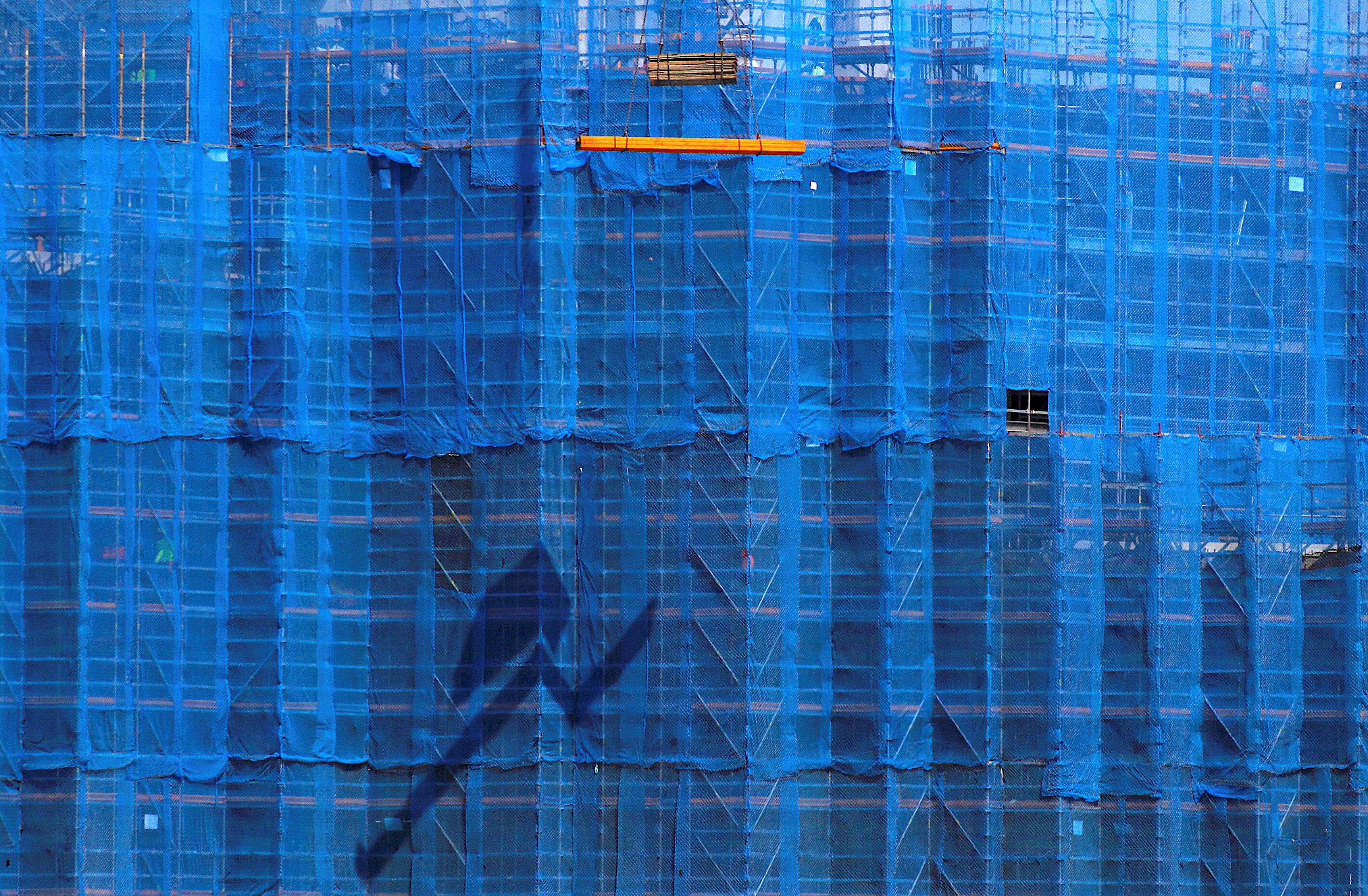 A crane lifts building materials in front of scaffolding at a construction site in central Sydney