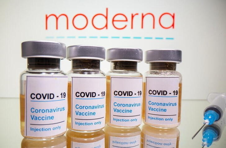 Vials and medical syringe are seen in front of Moderna logo in this illustration
