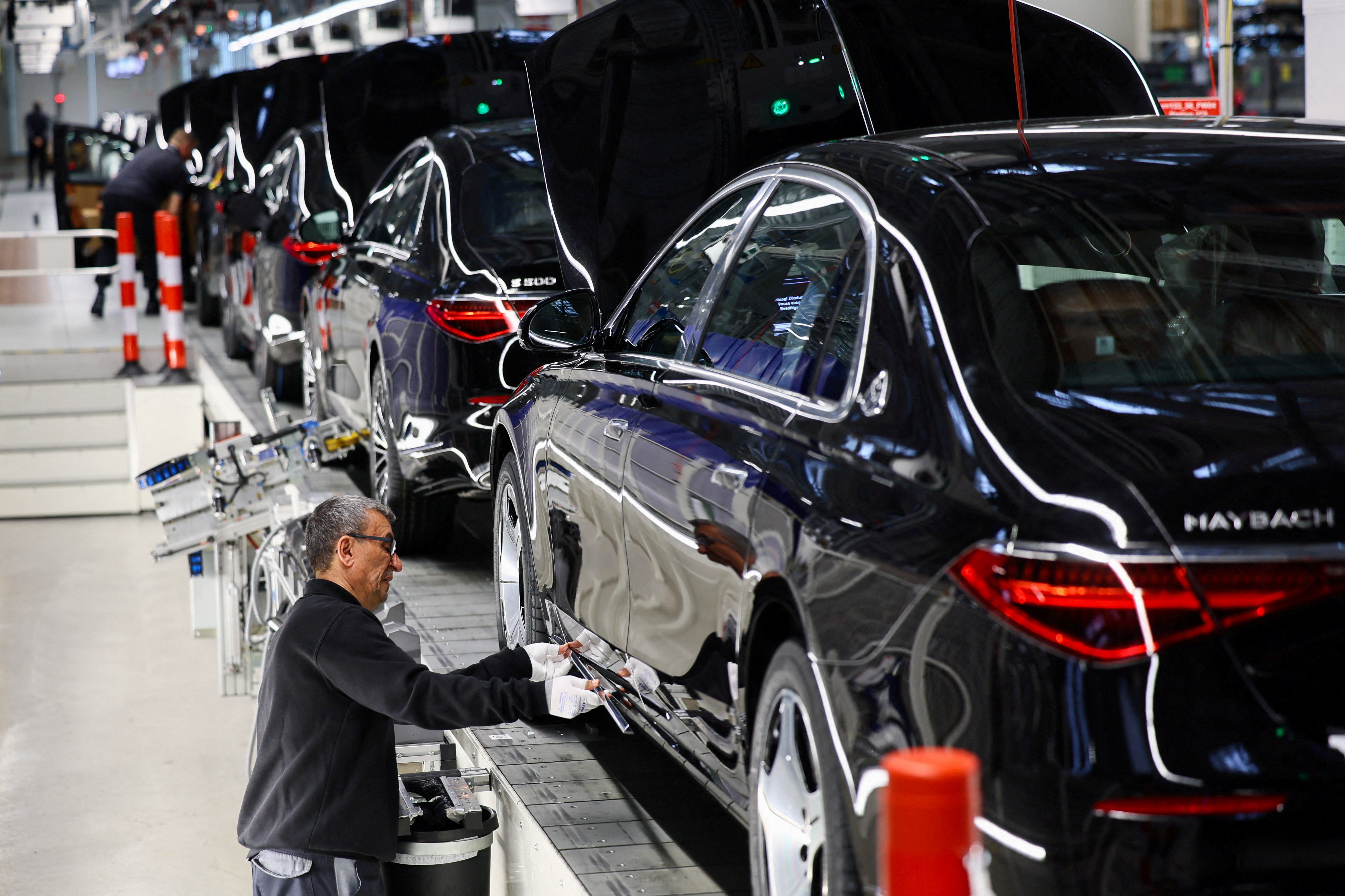 A worker attaches a part to a Mercedes-Maybach car on a production line of "Factory 56" in Sindelfingen