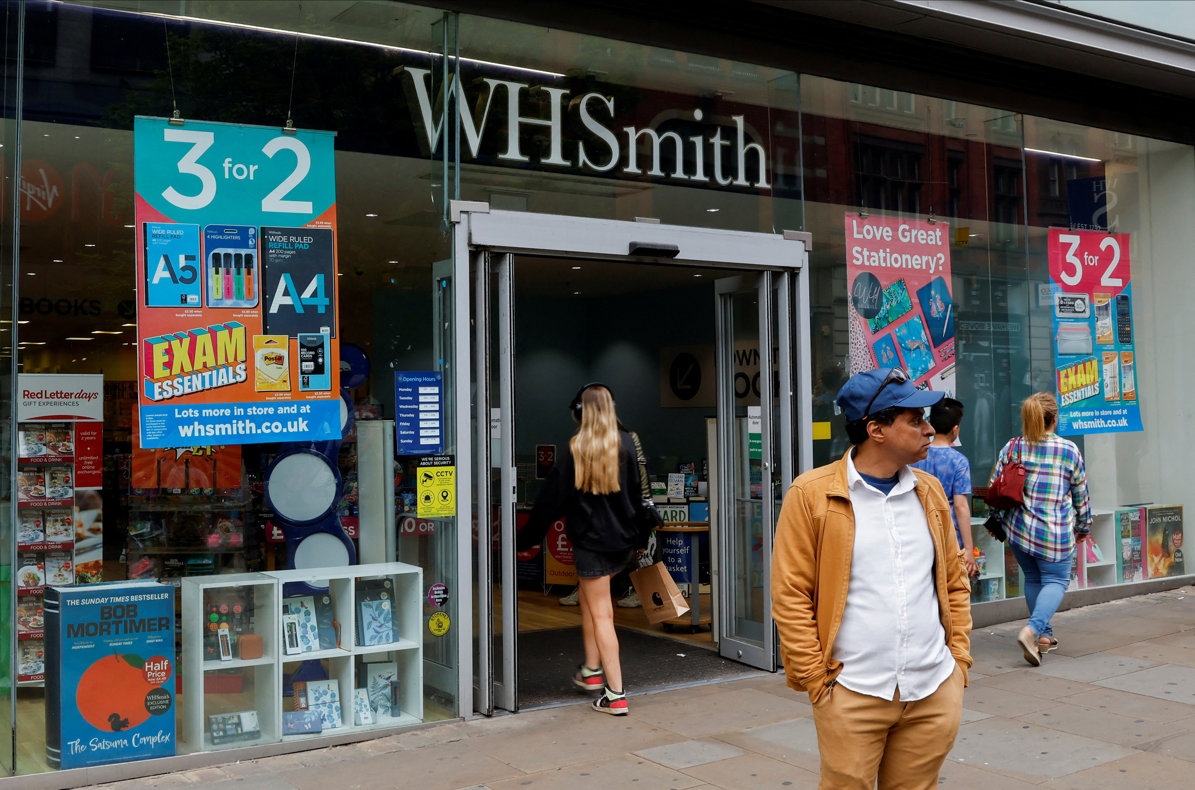 Man stands in front of a WH Smith store in Manchester