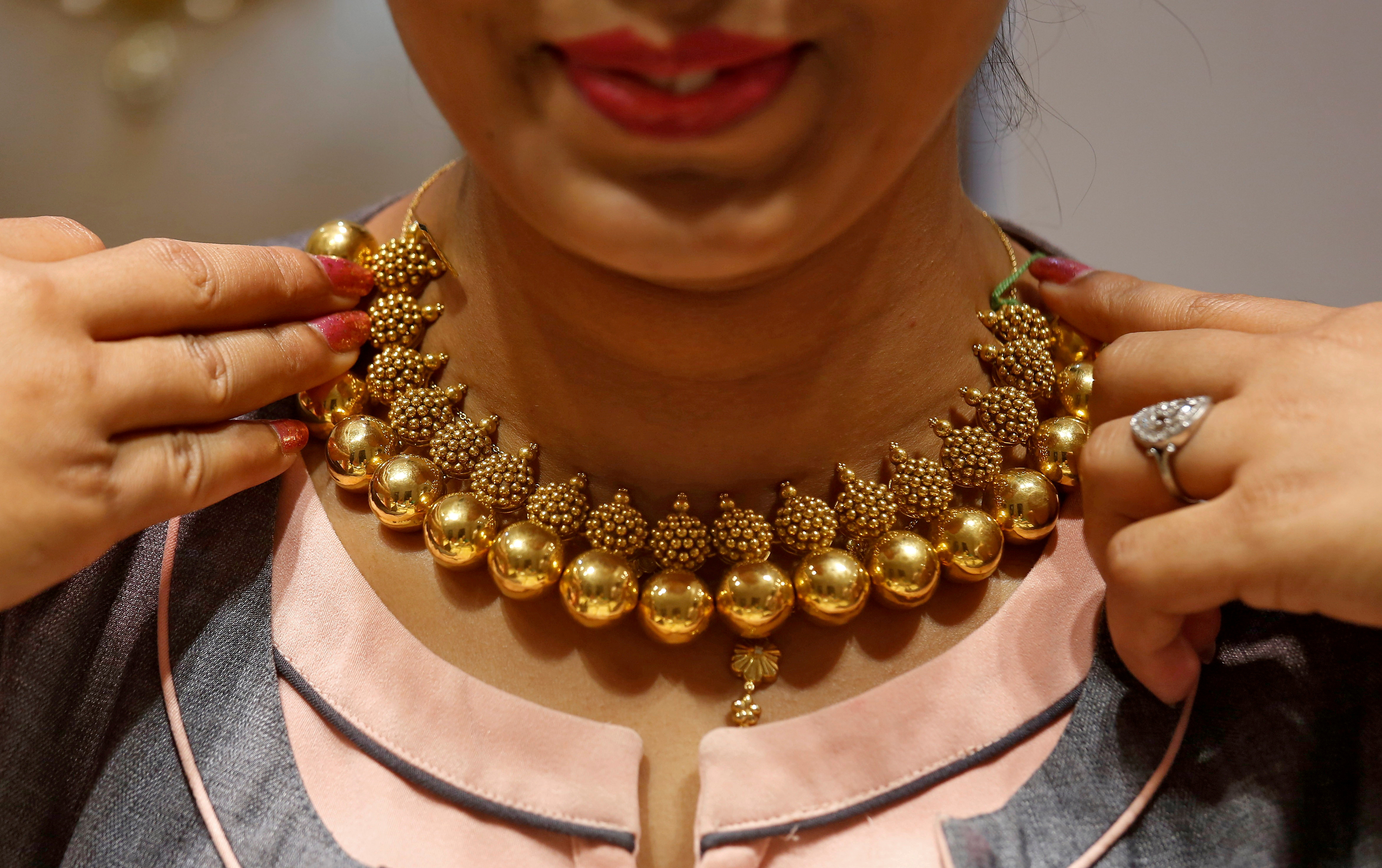 A saleswoman displays a gold necklace to a customer inside a jewellery showroom on the occasion of Akshaya Tritiya, a major gold buying festival, in Mumbai