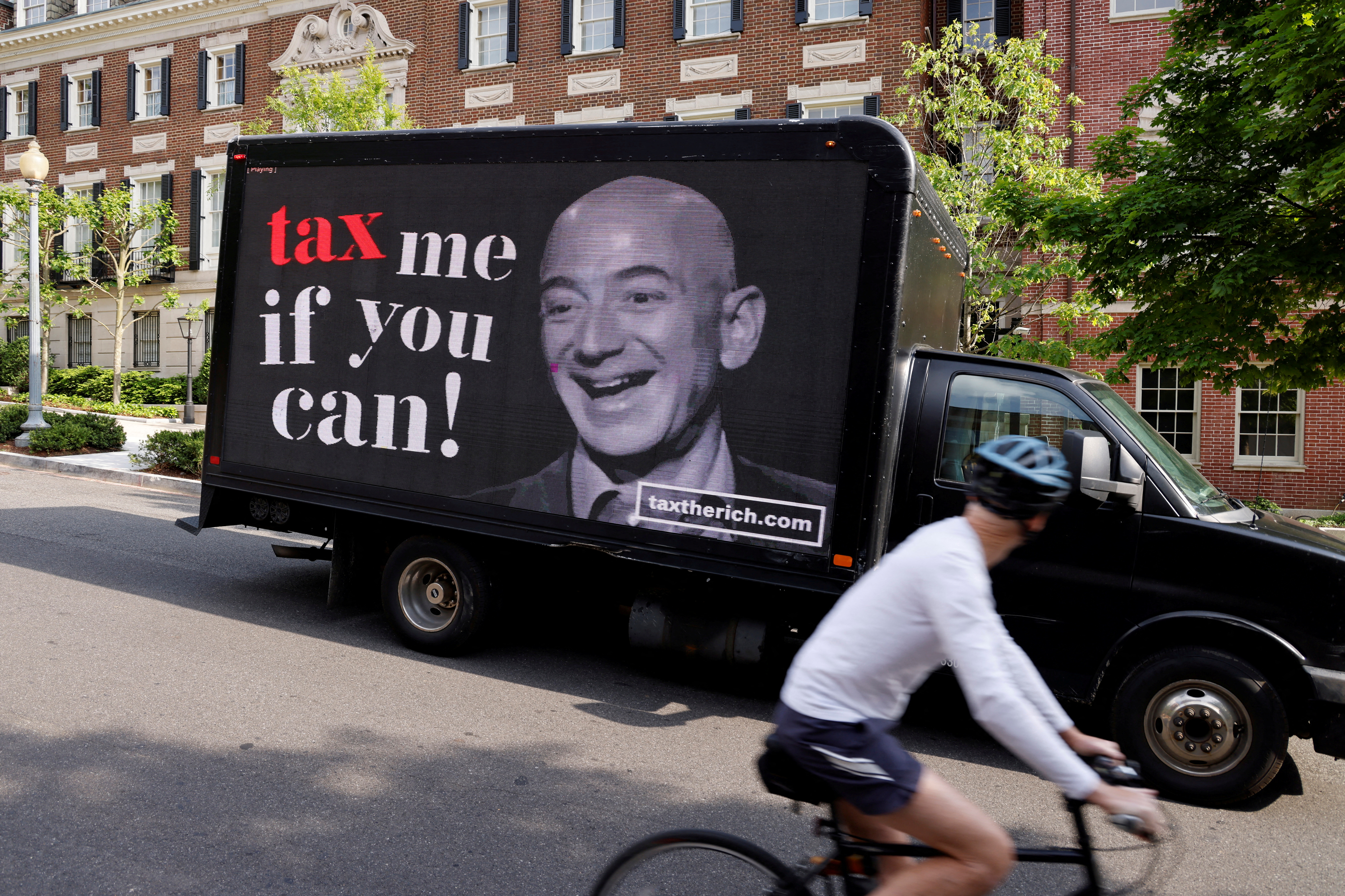 A video protest sign on a truck paid for by the Patriotic Millionaires drives past a mansion owned by Amazon founder Bezos in Washington