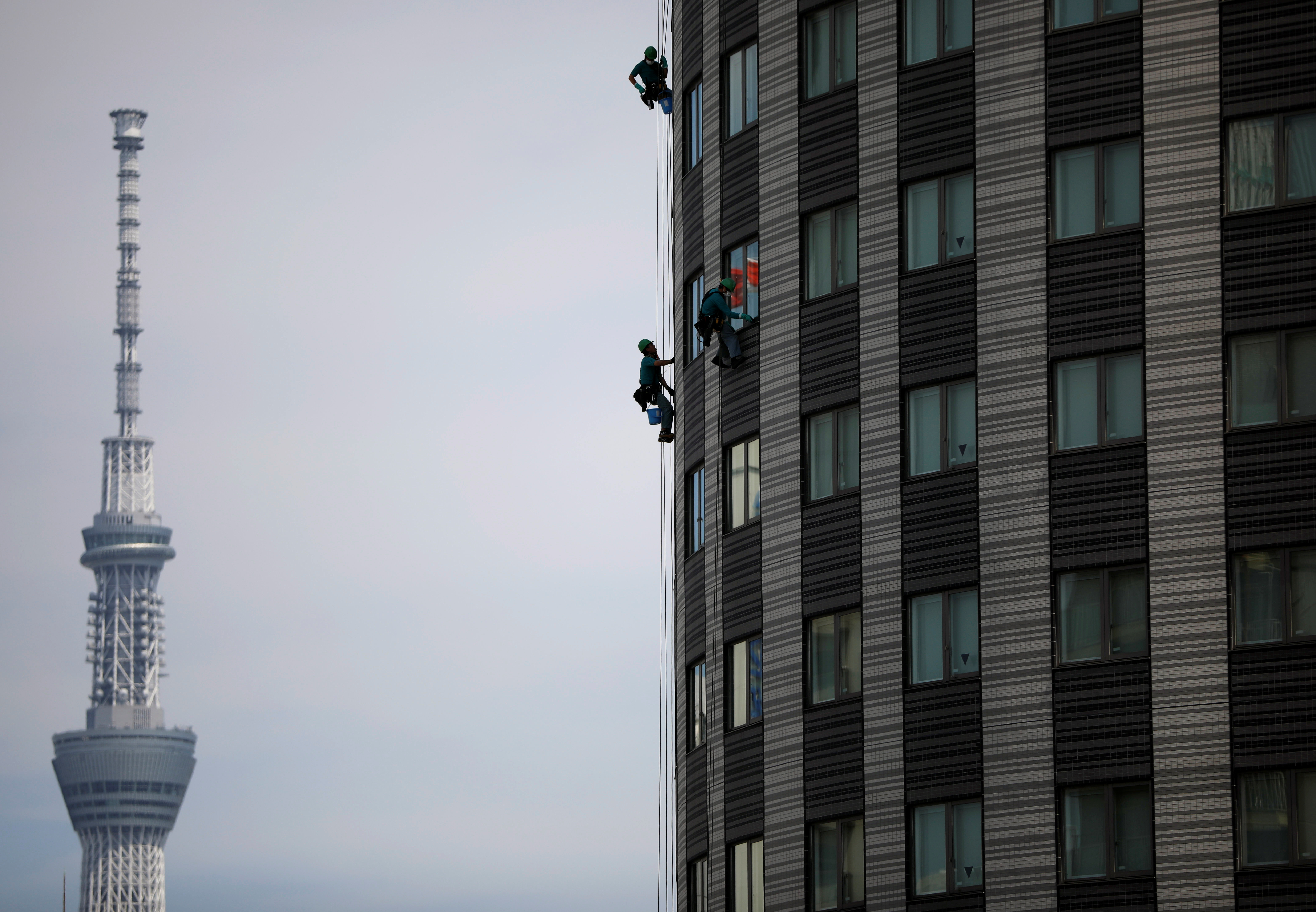 Workers clean the windows of a hotel with Tokyo Skytree, the world's tallest broadcasting tower, in the background during the spread of the coronavirus disease (COVID-19) in Tokyo