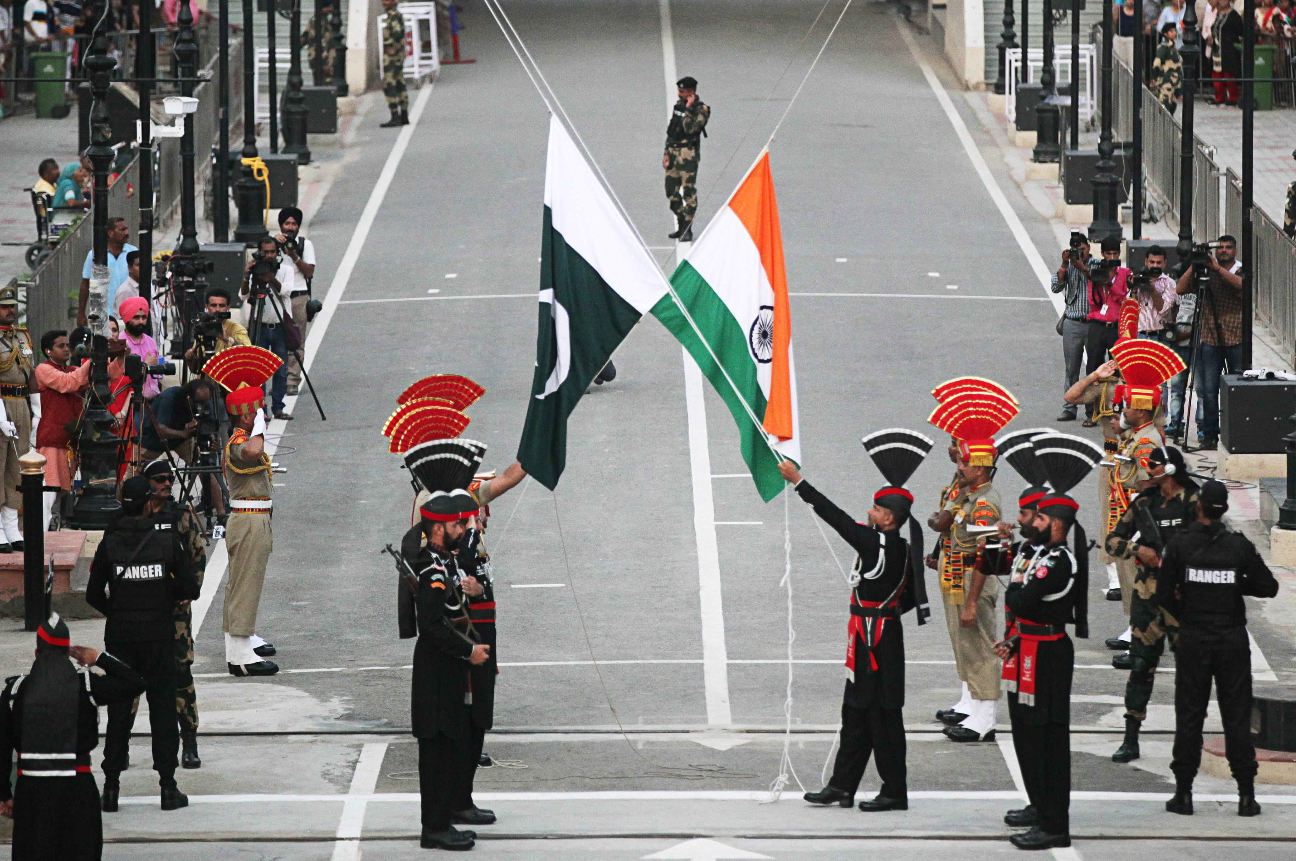 Pakistani Rangers (wearing black uniforms) and Indian Border Security Force (BSF) officers lower their national flags during parade on the Pakistan's 72nd Independence Day, at the Pakistan-India joint check-post at Wagah border, near Lahore, Pakistan August 14, 2019. REUTERS/Mohsin Raza