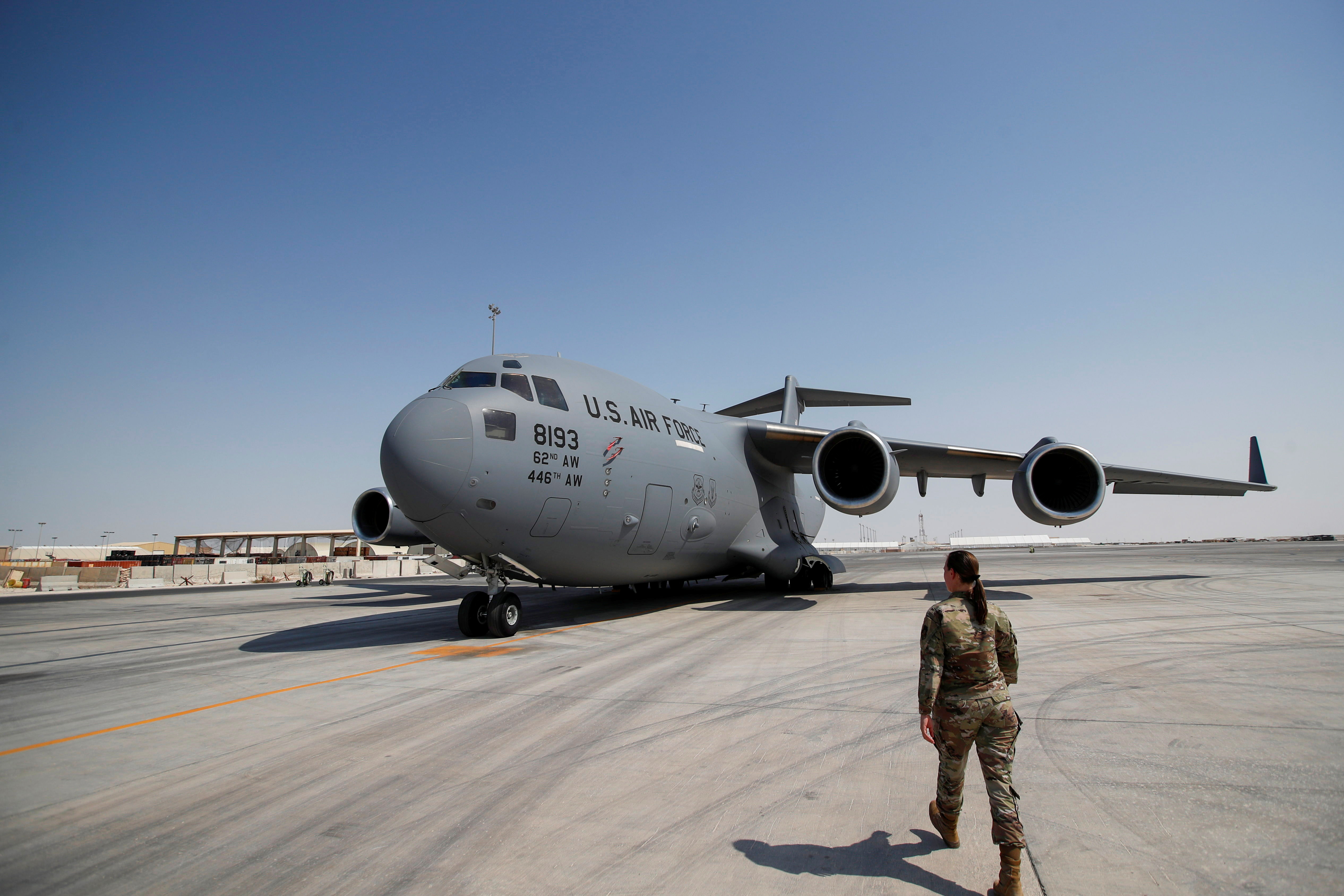A U.S. military officer walks towards a U.S. Air Force plane at Al Udeid airbase in Doha