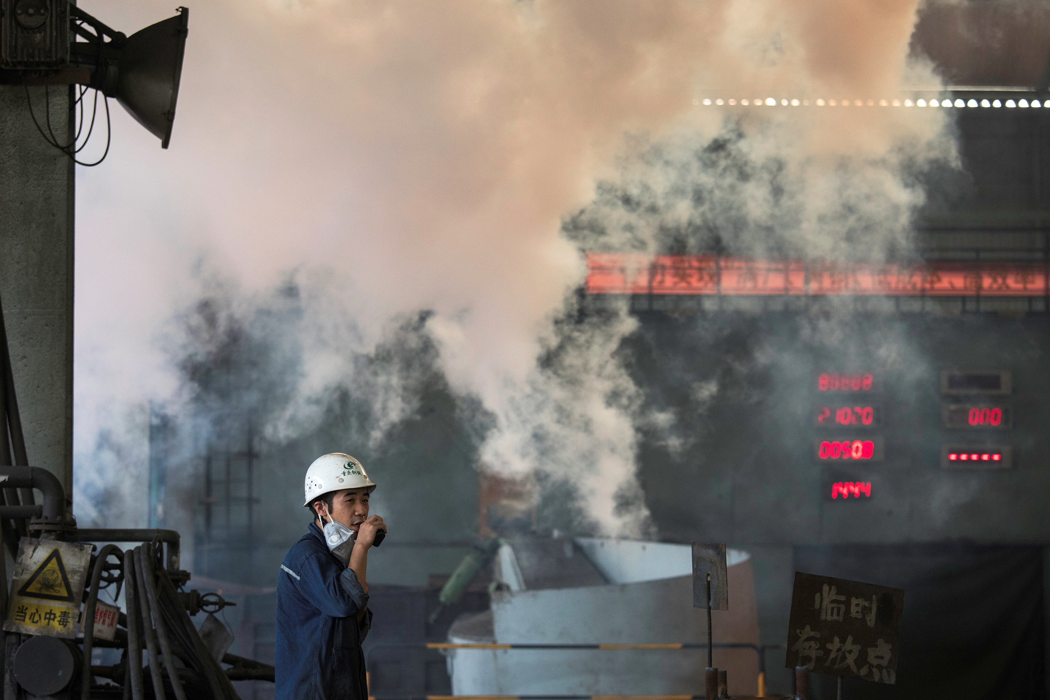 Worker stands near smoke from blast furnace at the Chongqing Iron and Steel plant in Changshou