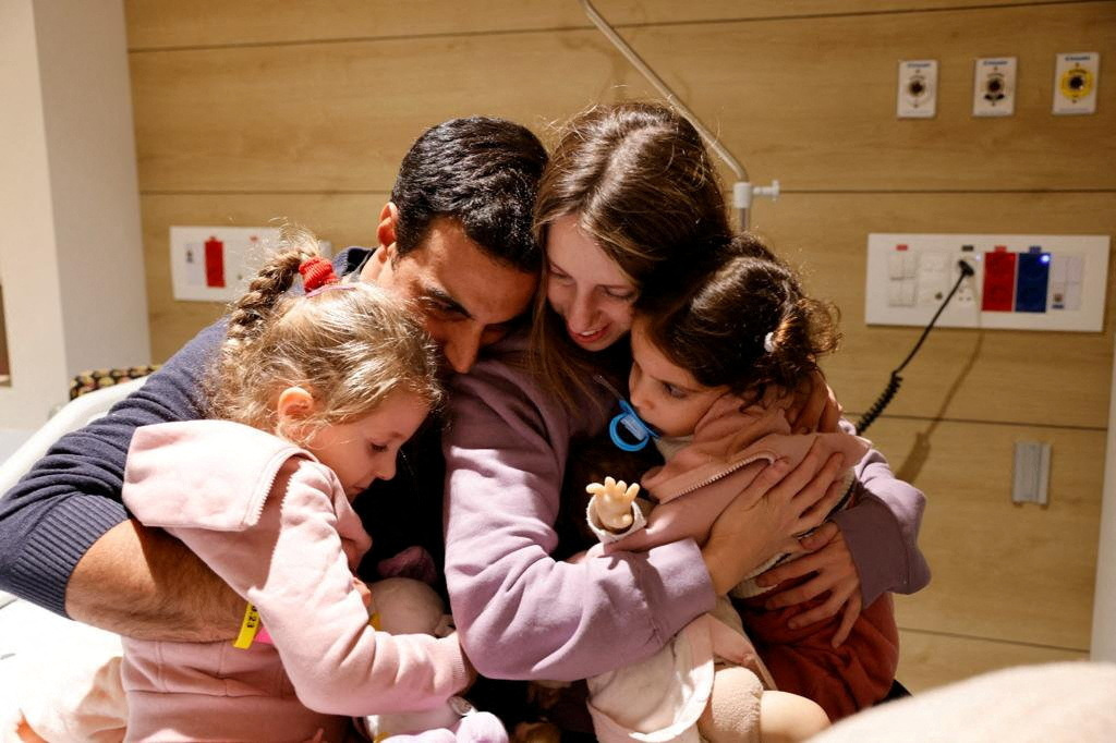 Aviv Asher, 2,5-year-old, her sister Raz Asher, 4,5-year-old, and mother Doron, react as they meet with Yoni, Raz and Aviv's father and Doron's husband, after they returned to Israel