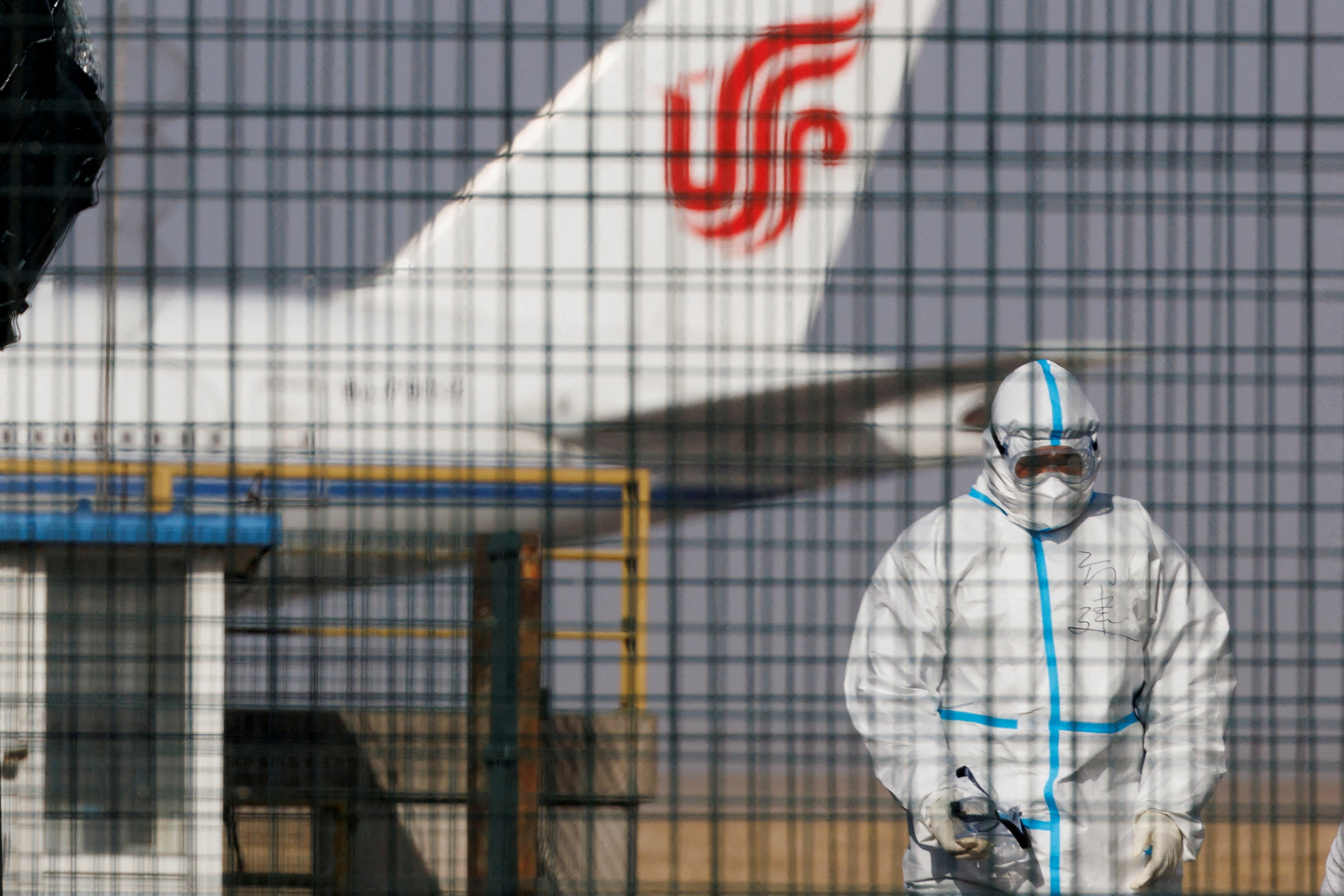 Un travailleur en tenue de protection marche près d'un avion des compagnies aériennes Air China à l'aéroport international de Pékin alors que les épidémies de coronavirus (COVID-19) se poursuivent à Pékin