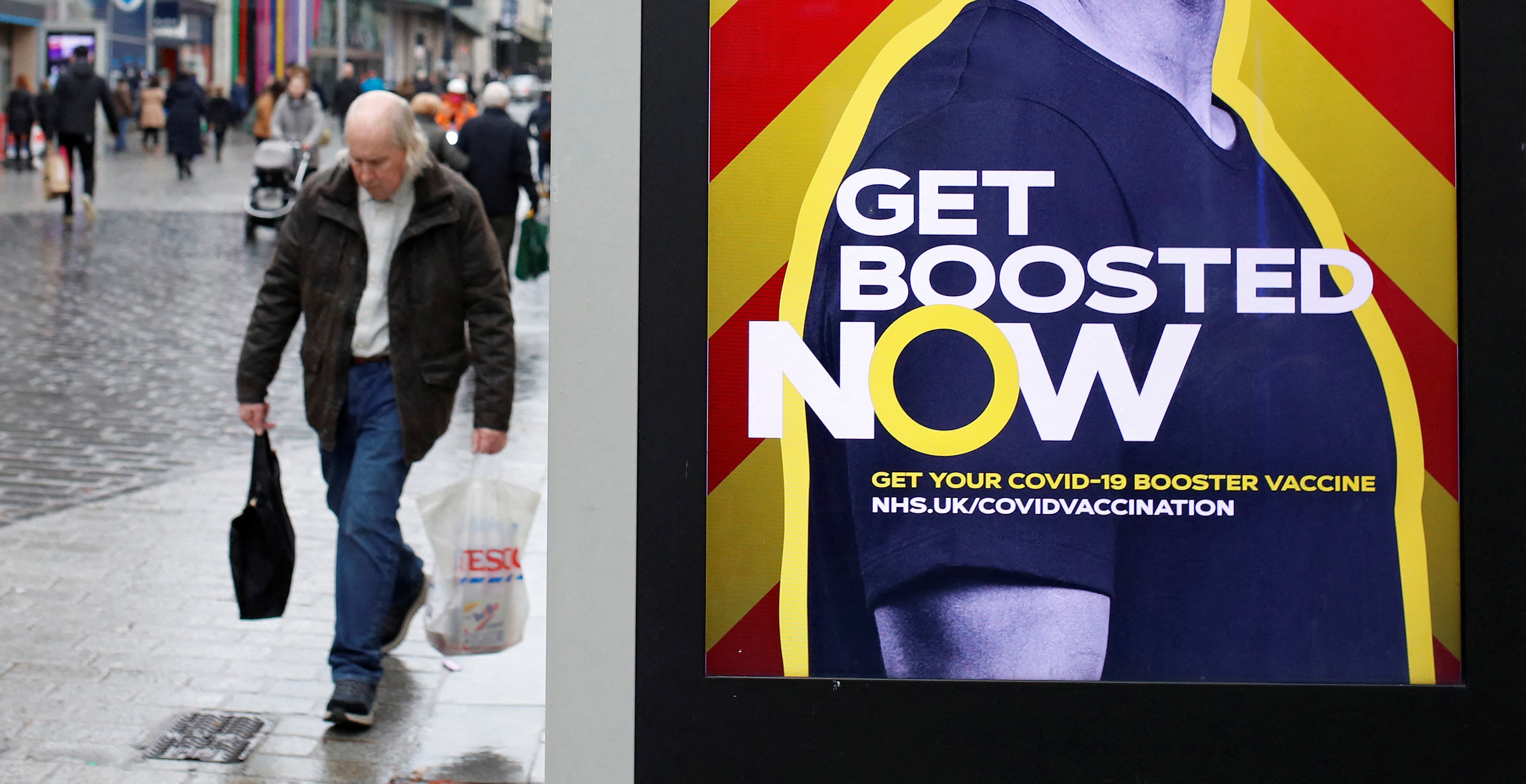 A man walks past an advertising board encouraging people to get their booster vaccination, amid the coronavirus disease (COVID-19) outbreak in Liverpool