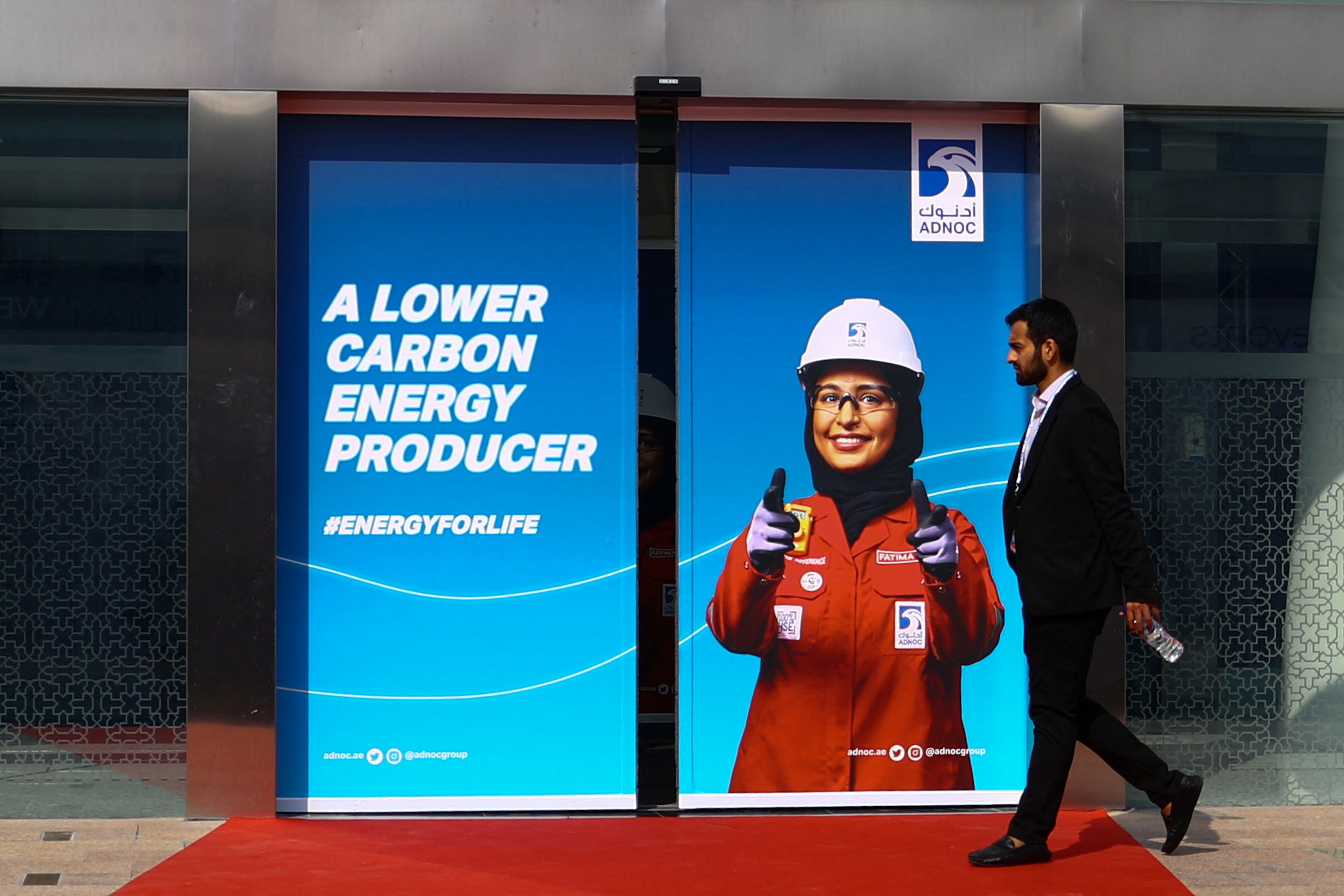 A person walks past a Abu Dhabi National Oil Company (ADNOC) poster during the Abu Dhabi International Petroleum Exhibition and Conference (ADIPEC) in Abu Dhabi