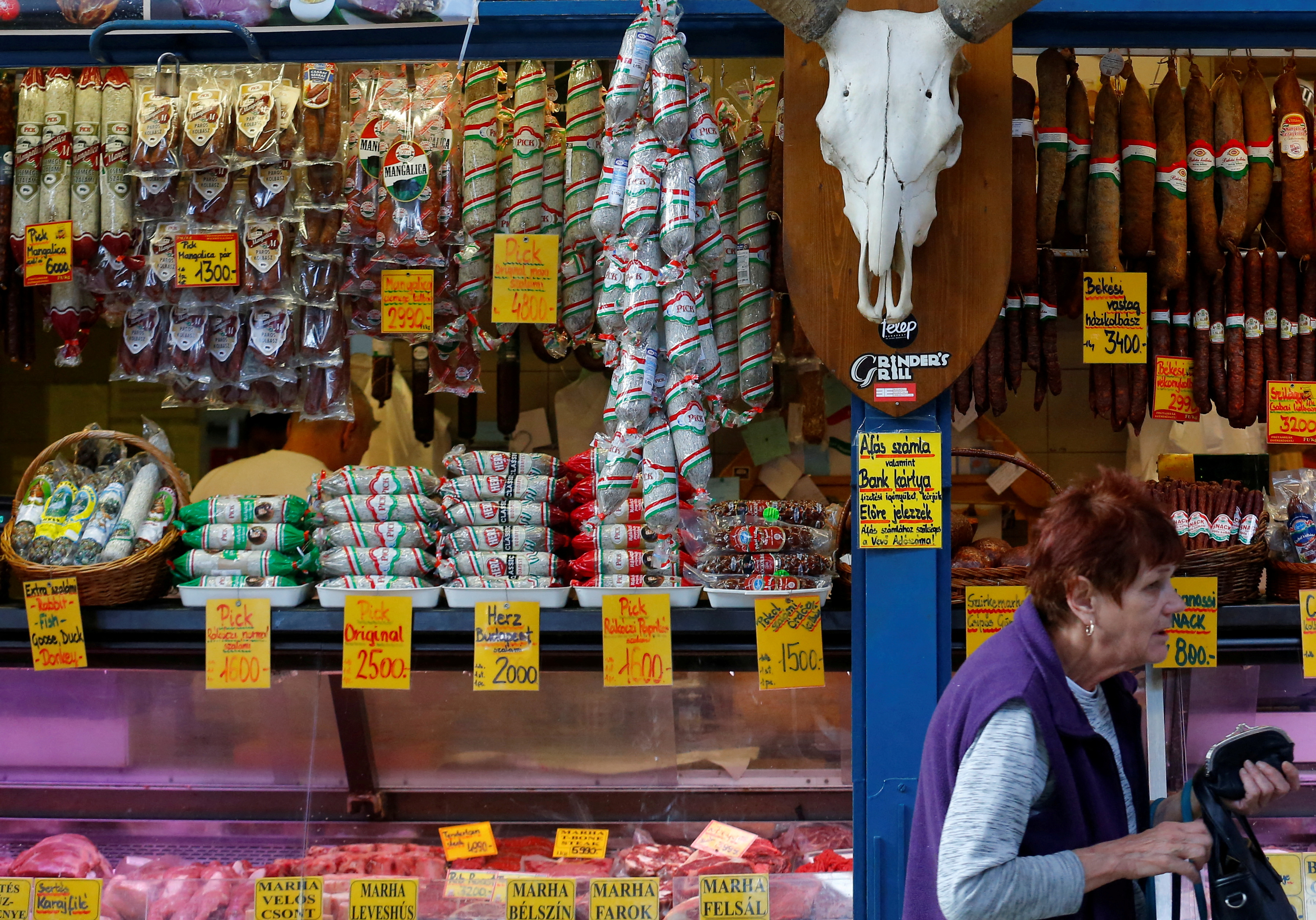 A shopper walks by the stand of a meat vendor at the Grand Market hall in Budapest, Hungary