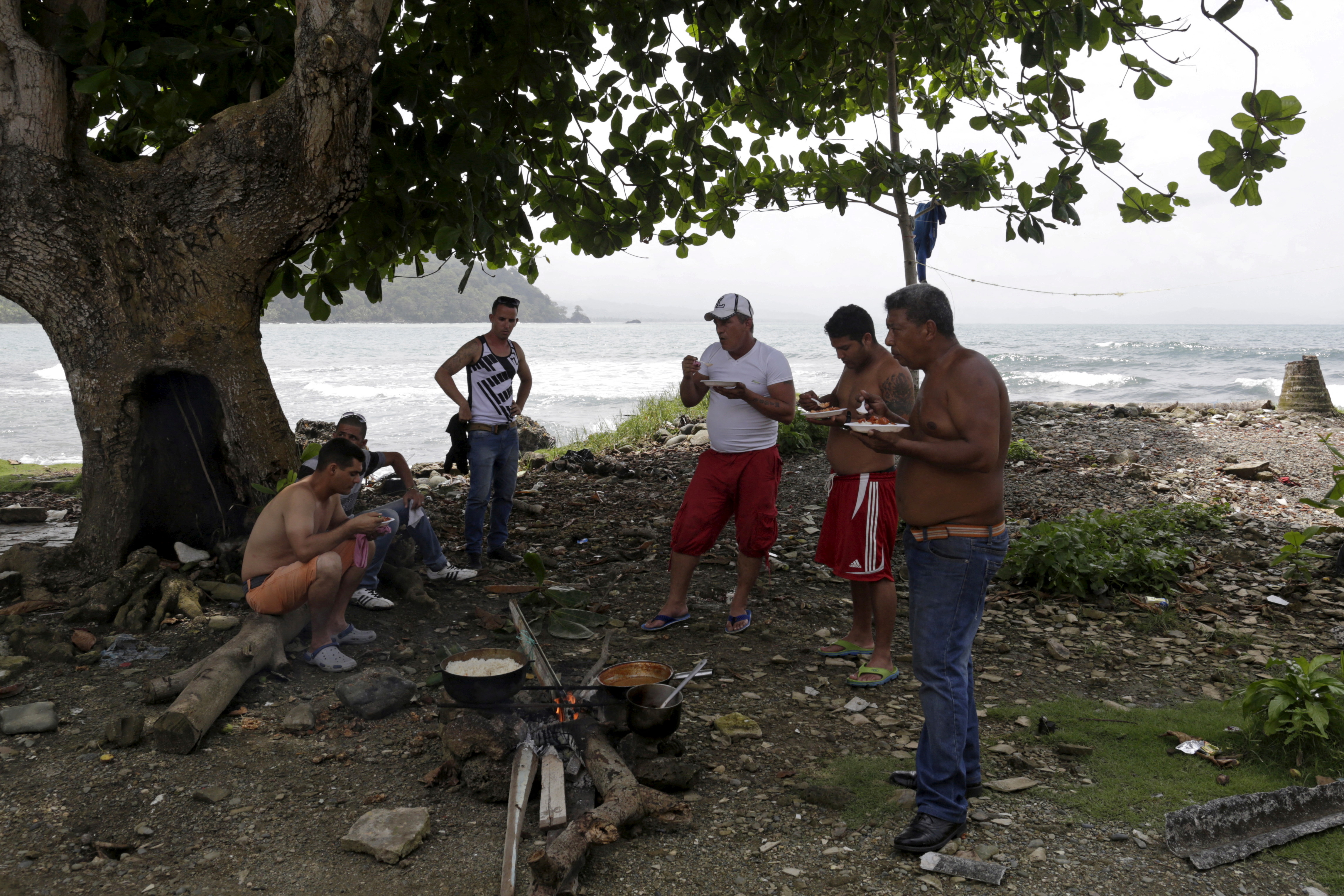 Migrantes cubanos comen junto a una fogata en la ciudad de Puerto Obaldía, en la región panameña de Guana Yala