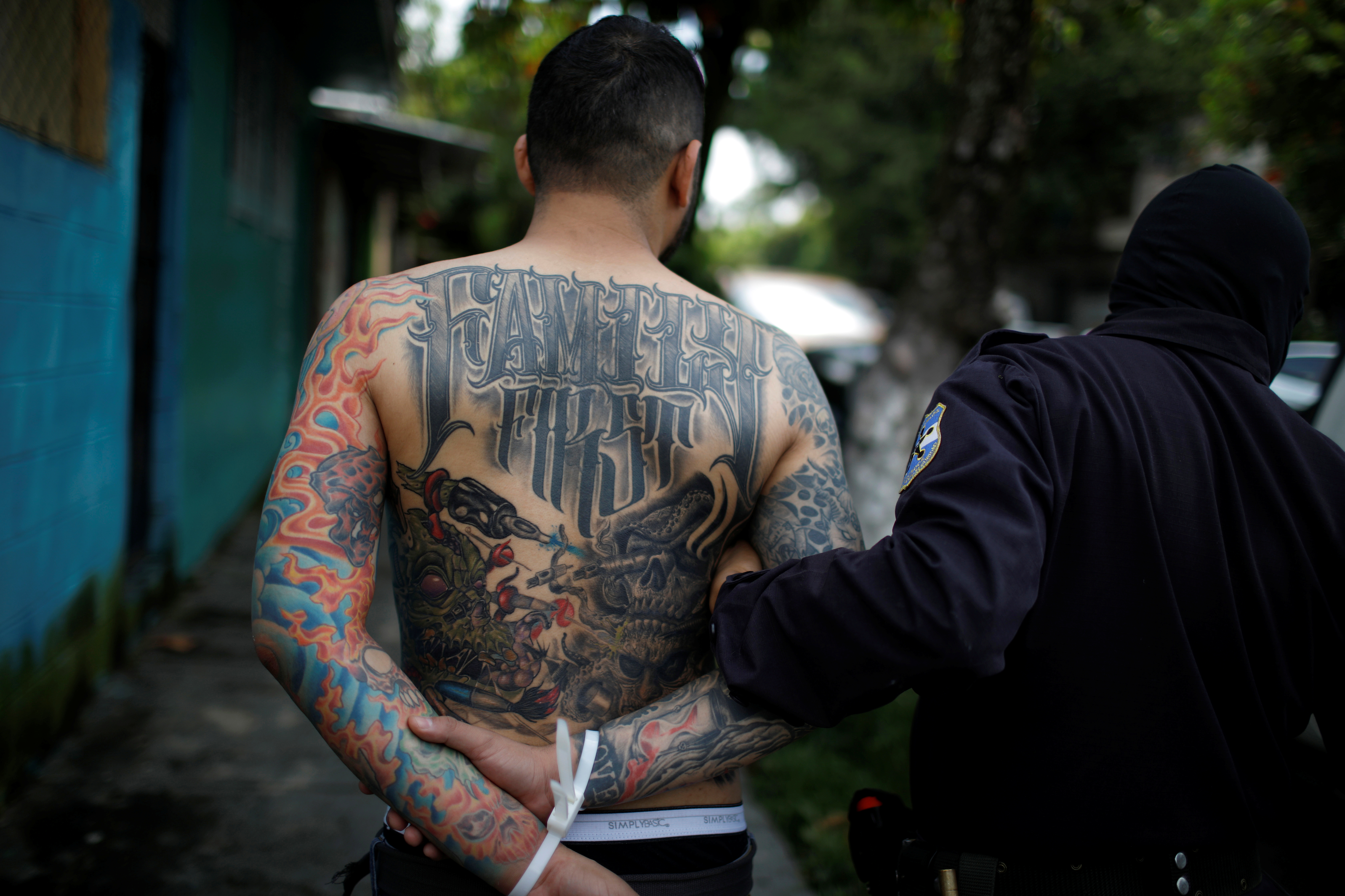 A police officer detains a man in a seized MS-13 gang usurped house during a "Casa Segura" (Safe House) operation at Jardines de San Bartolo neighborhood, in Ilopango