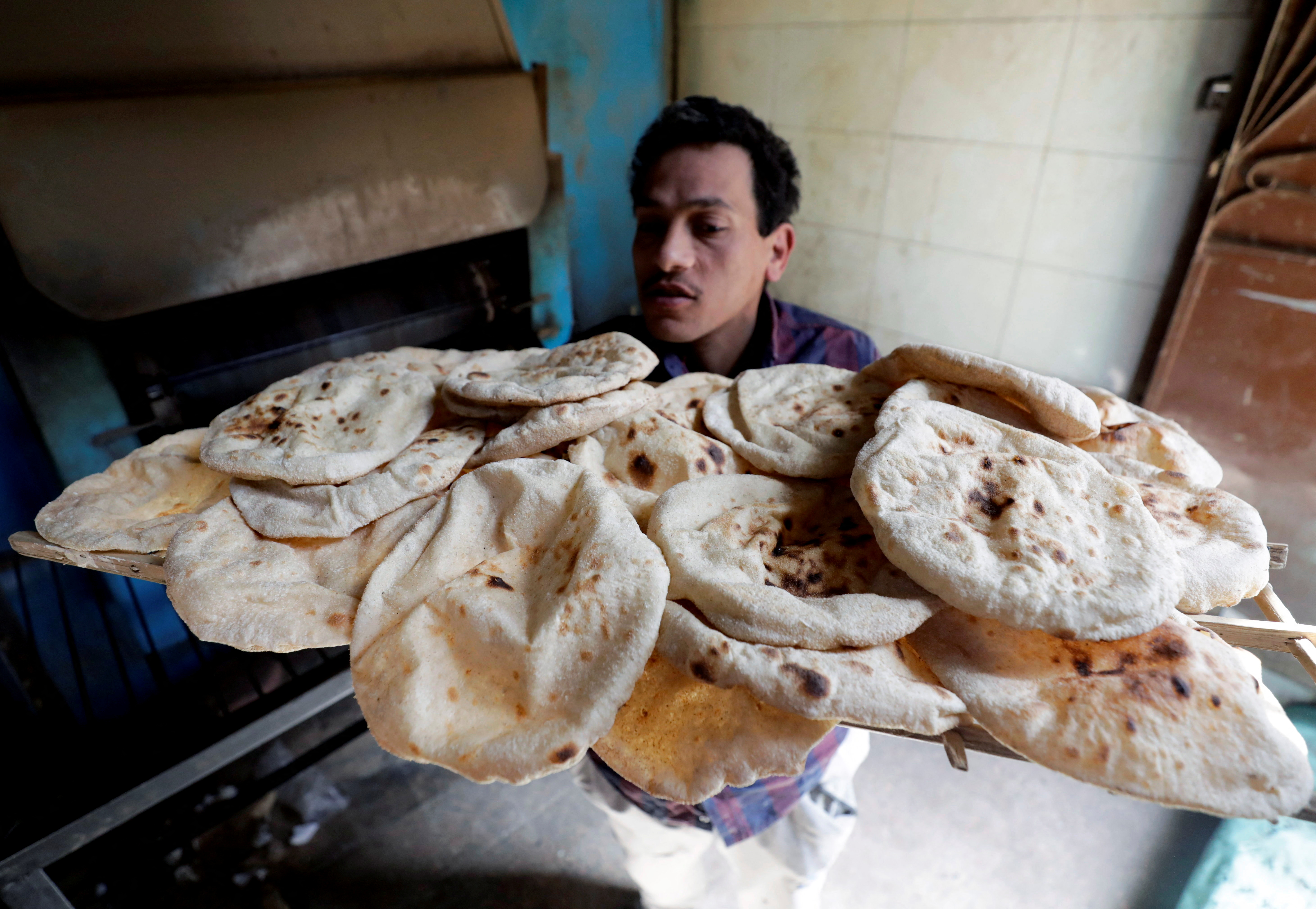 A baker carries bread in El-Kalubia governorate, northeast of Cairo