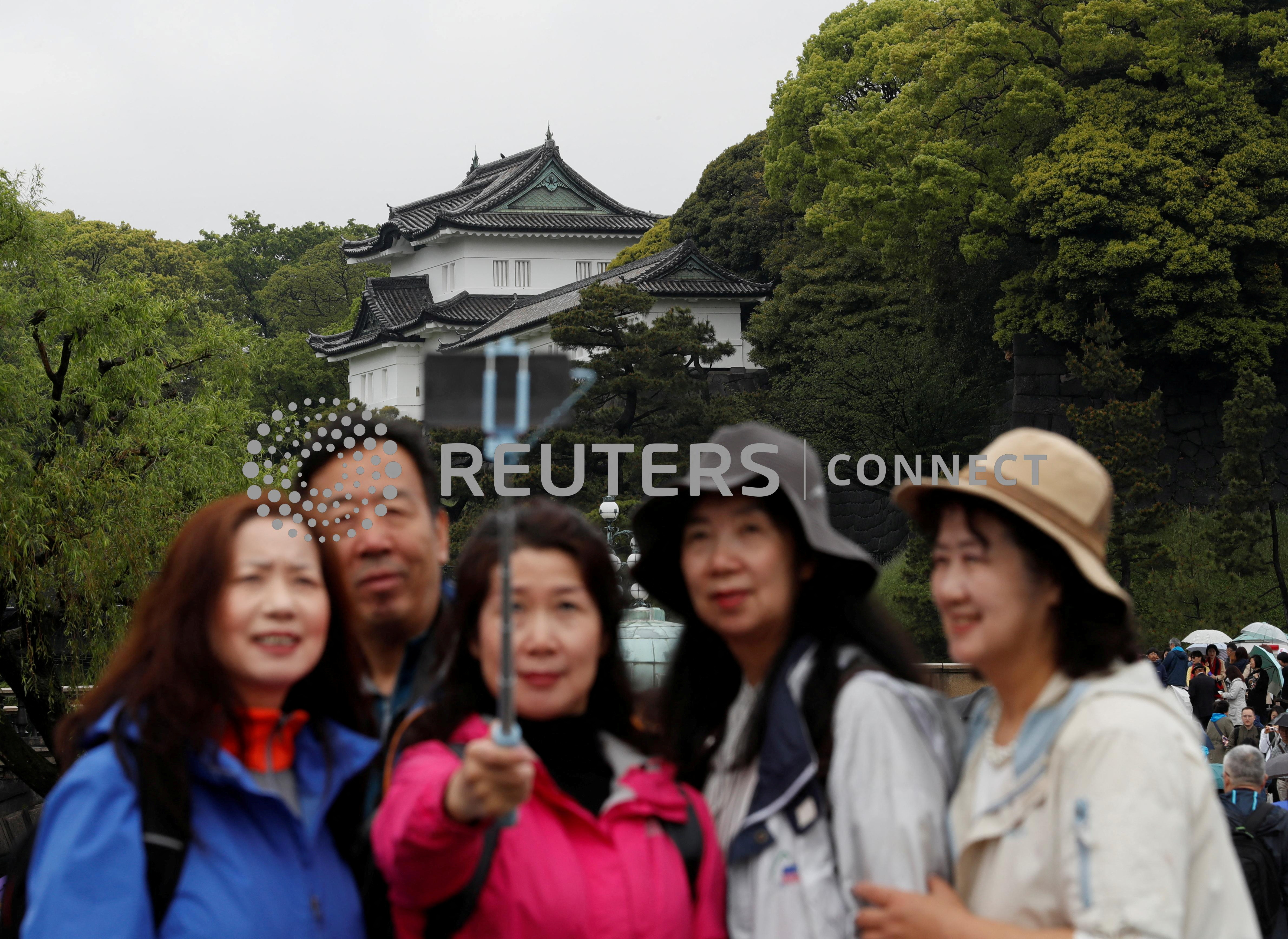 Chinese tourists take photos in front of the Imperial Palace in Tokyo