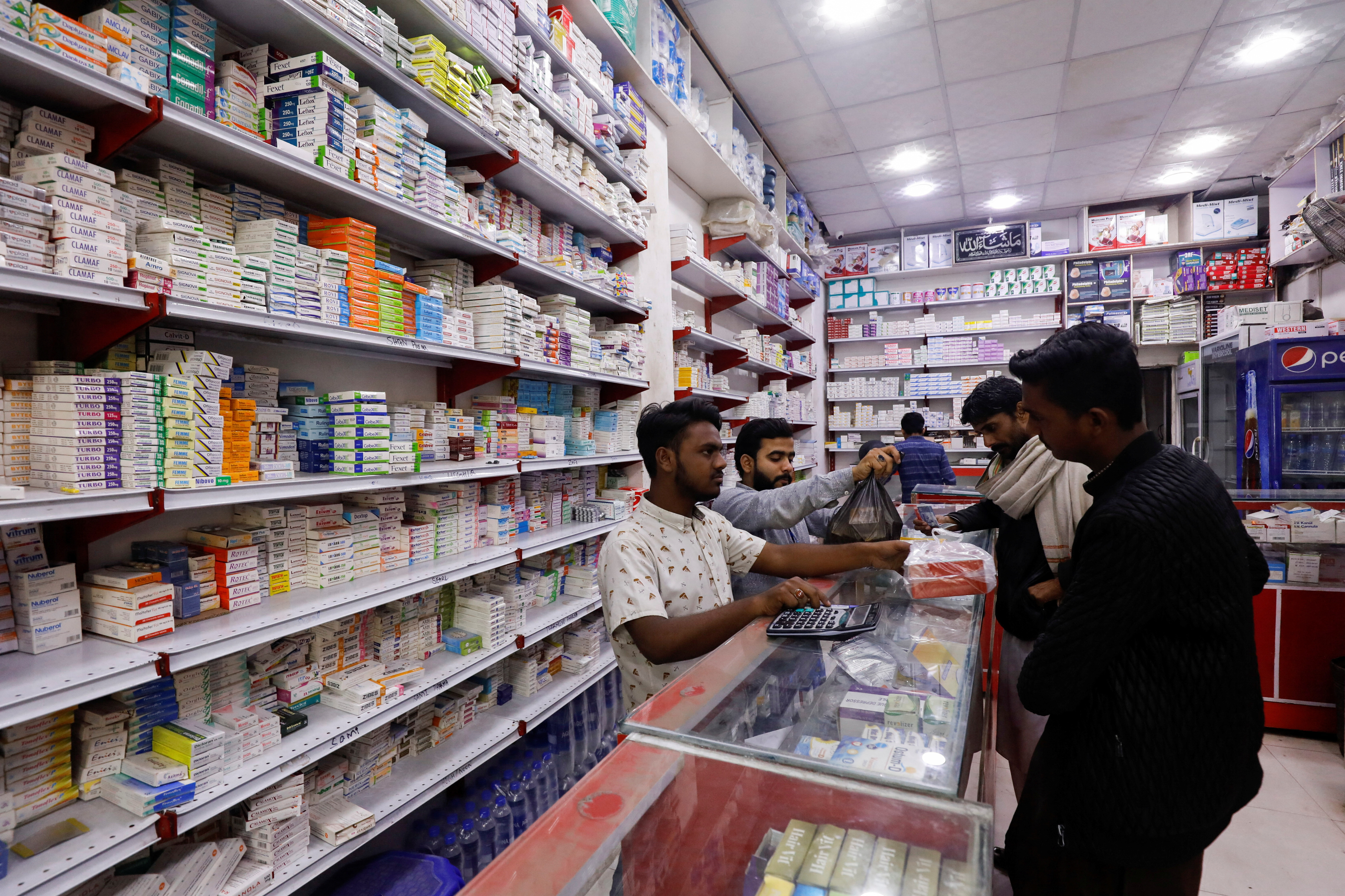 Customers buy medicine from a medical supply store in Karachi