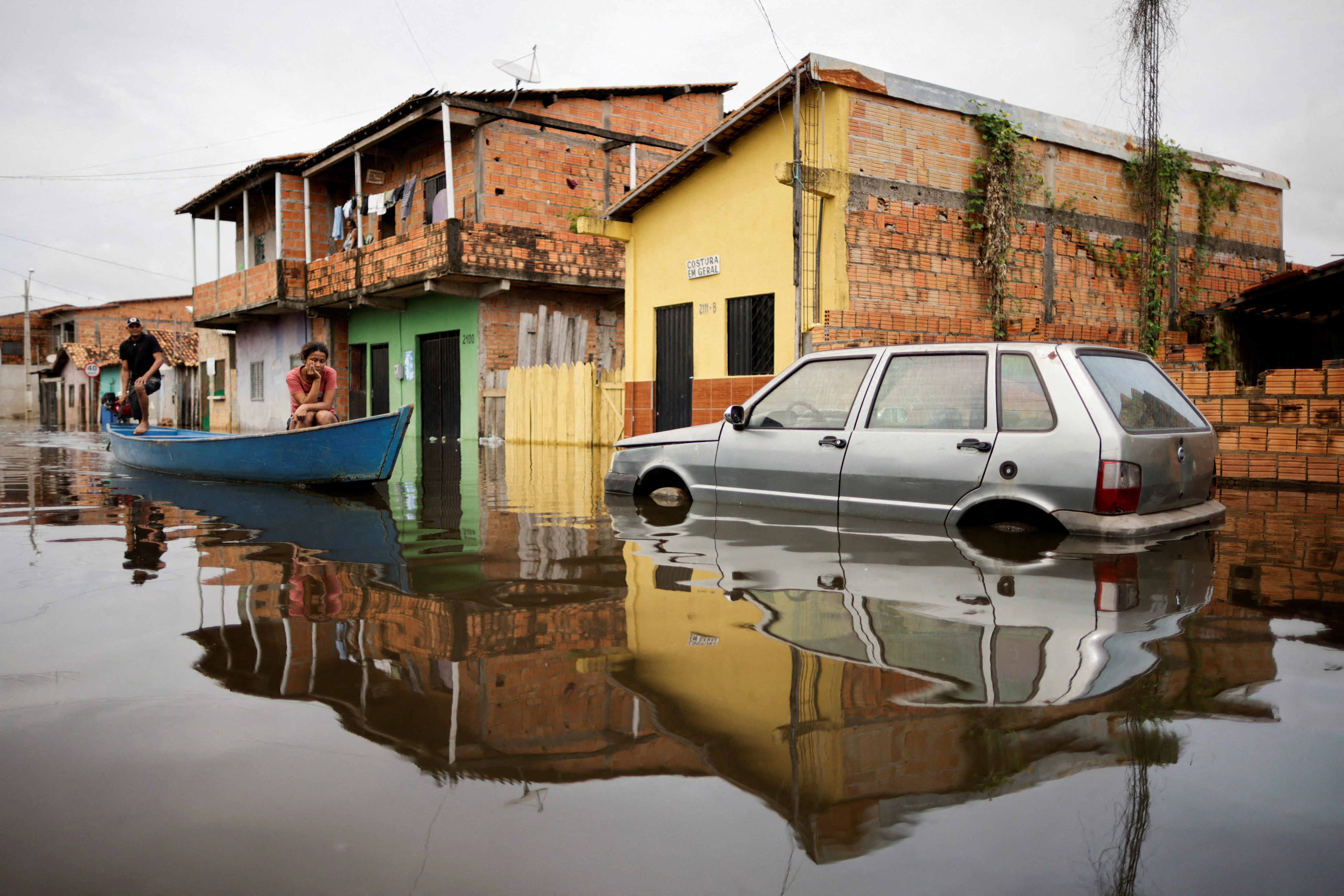 People in a canoe cross a car on a flooded street during floods caused by heavy rain in Maraba, Para state, Brazil January 9, 2022. REUTERS/Ueslei Marcelino