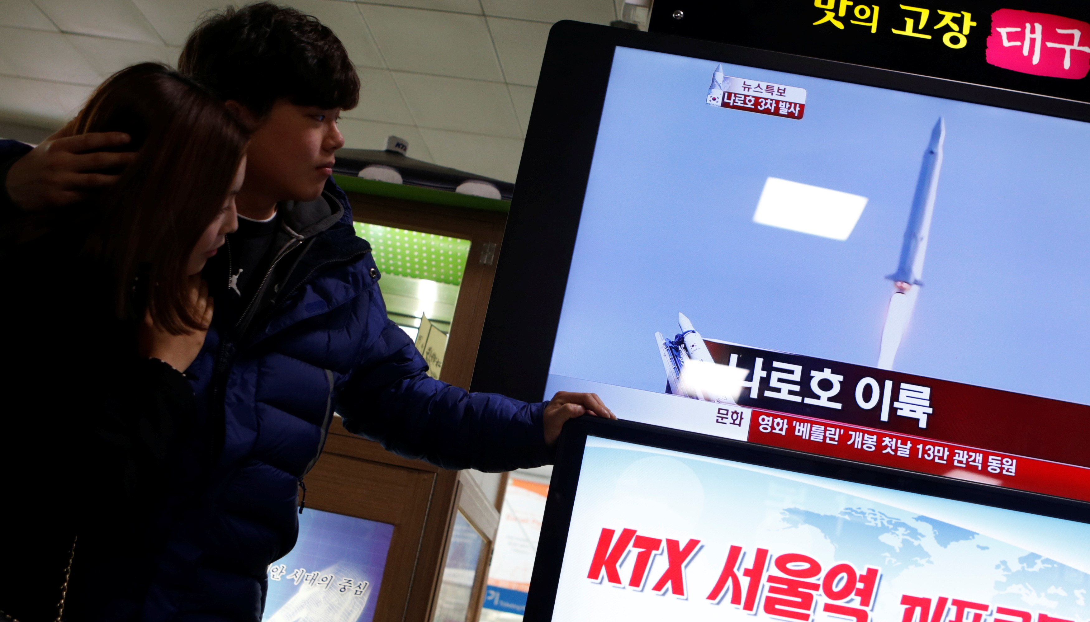 A couple watch a television report broadcasting the launch of South Korea's space rocket Korea Space Launch Vehicle-1 (KSLV-1) or Naro at Naro Space Centre in Goheung, about 485 km (301 miles) south of Seoul, at a train station in Seoul January 30, 2013.  REUTERS/Lee Jae-Won (SOUTH KOREA - Tags: SCIENCE TECHNOLOGY POLITICS)/File Photo
