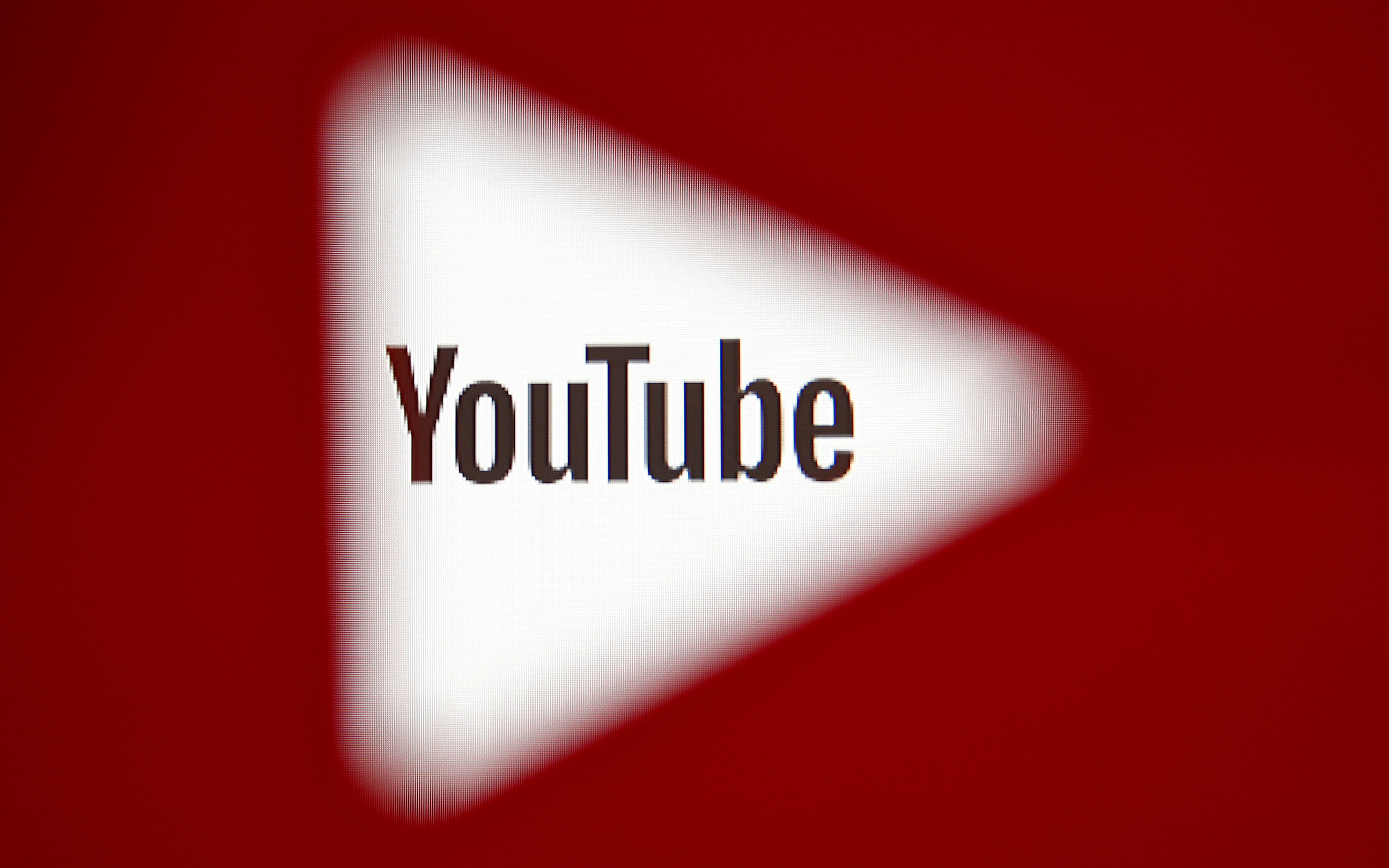 A 3D-printed YouTube icon is seen in front of a displayed YouTube logo in this illustration