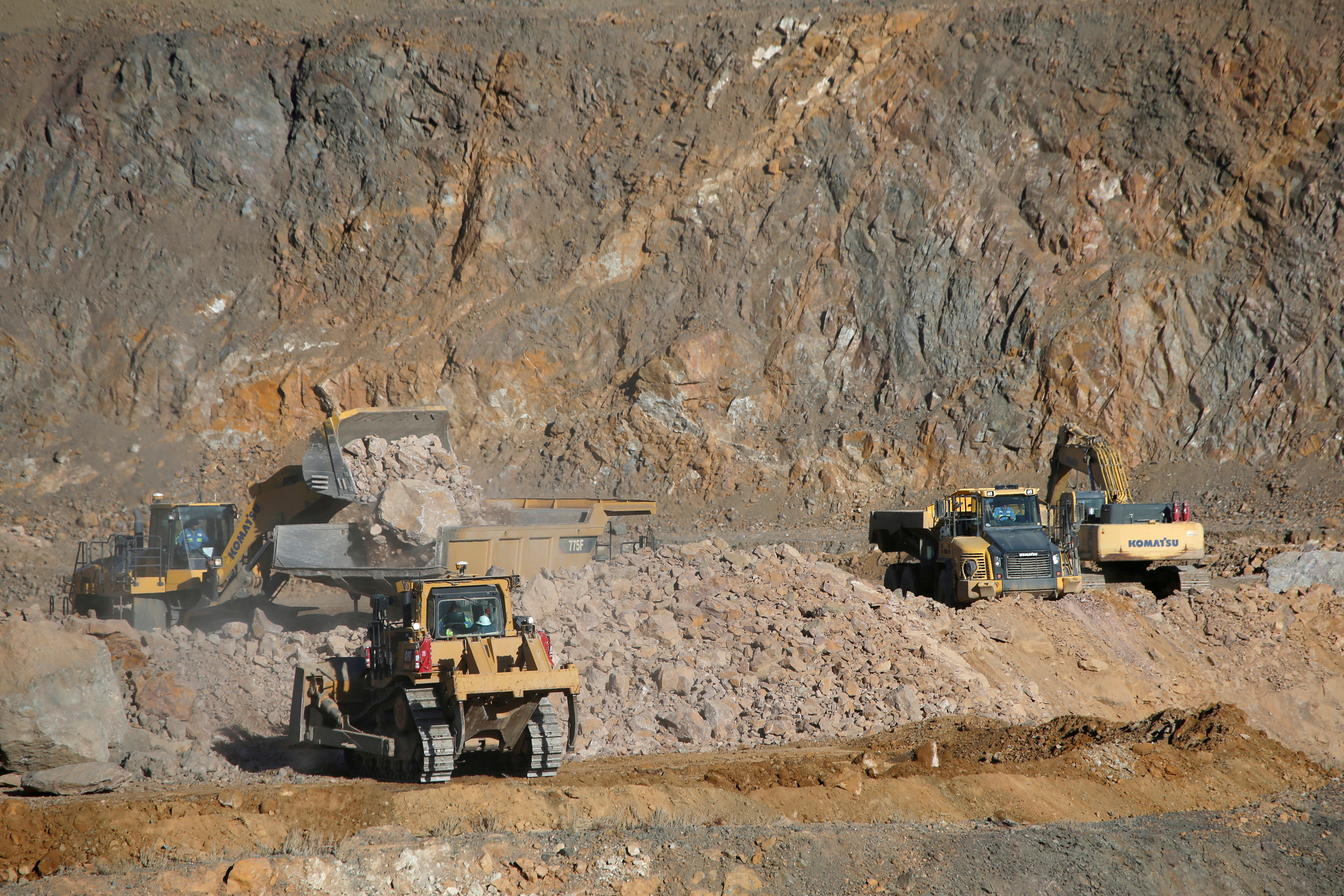 Wheel loaders fill trucks with ore at the MP Materials rare earth mine in Mountain Pass