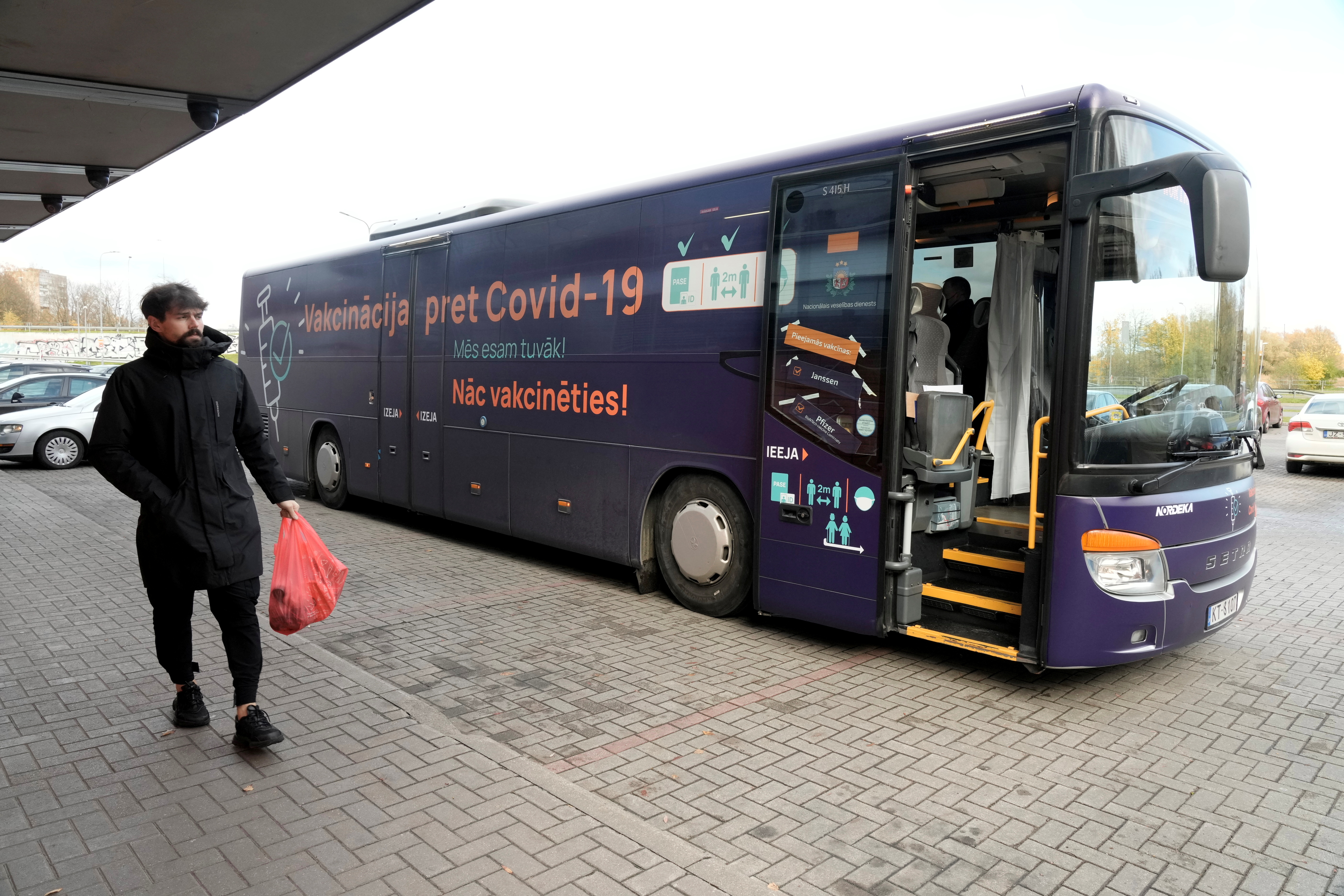 A man walks past a mobile coronavirus disease (COVID-19) vaccination bus next to the shopping center in Riga, Latvia October 19, 2021. Signs on a bus read 