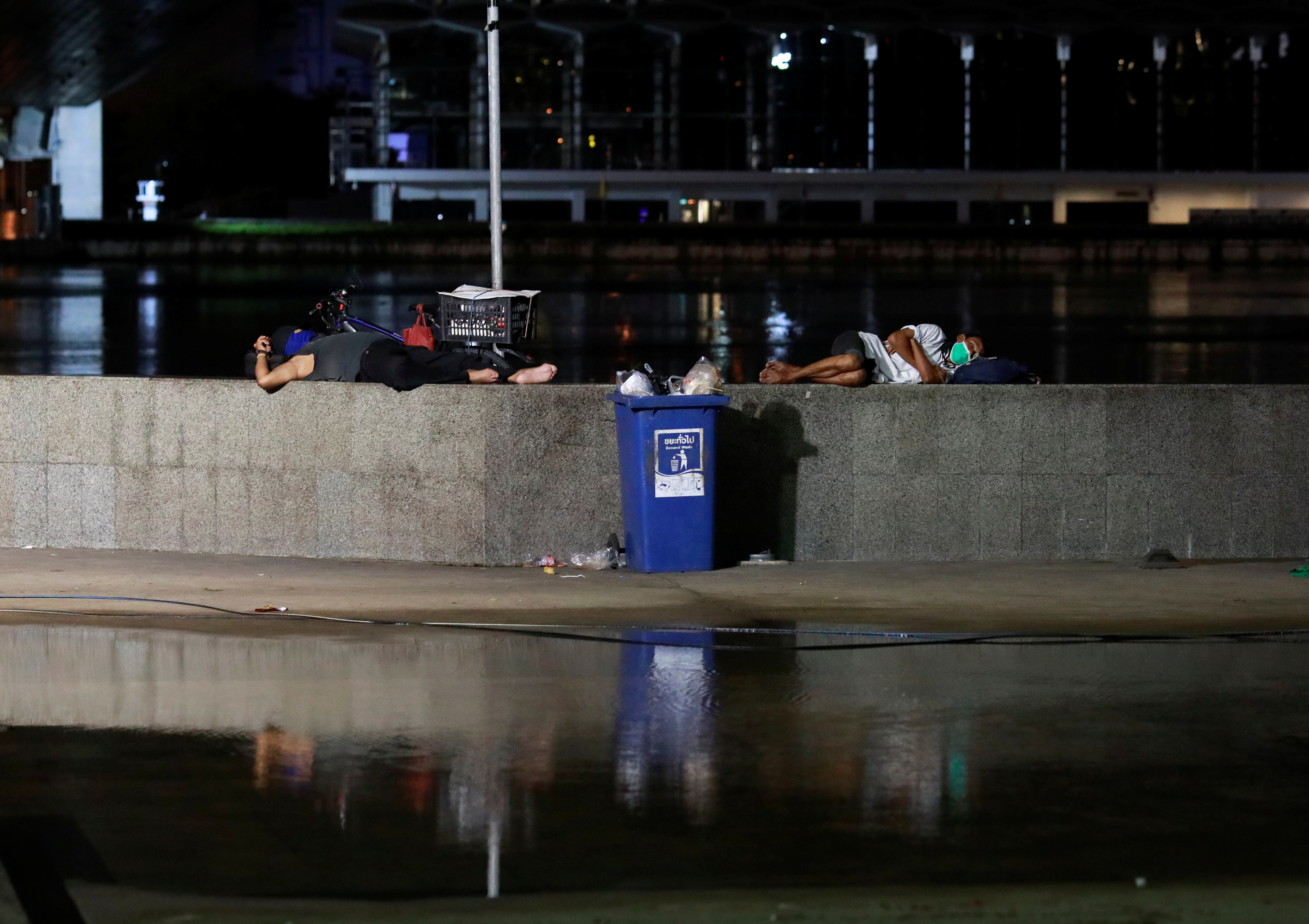 People sleep under a bridge as they wait for a free COVID-19 test in Bangkok