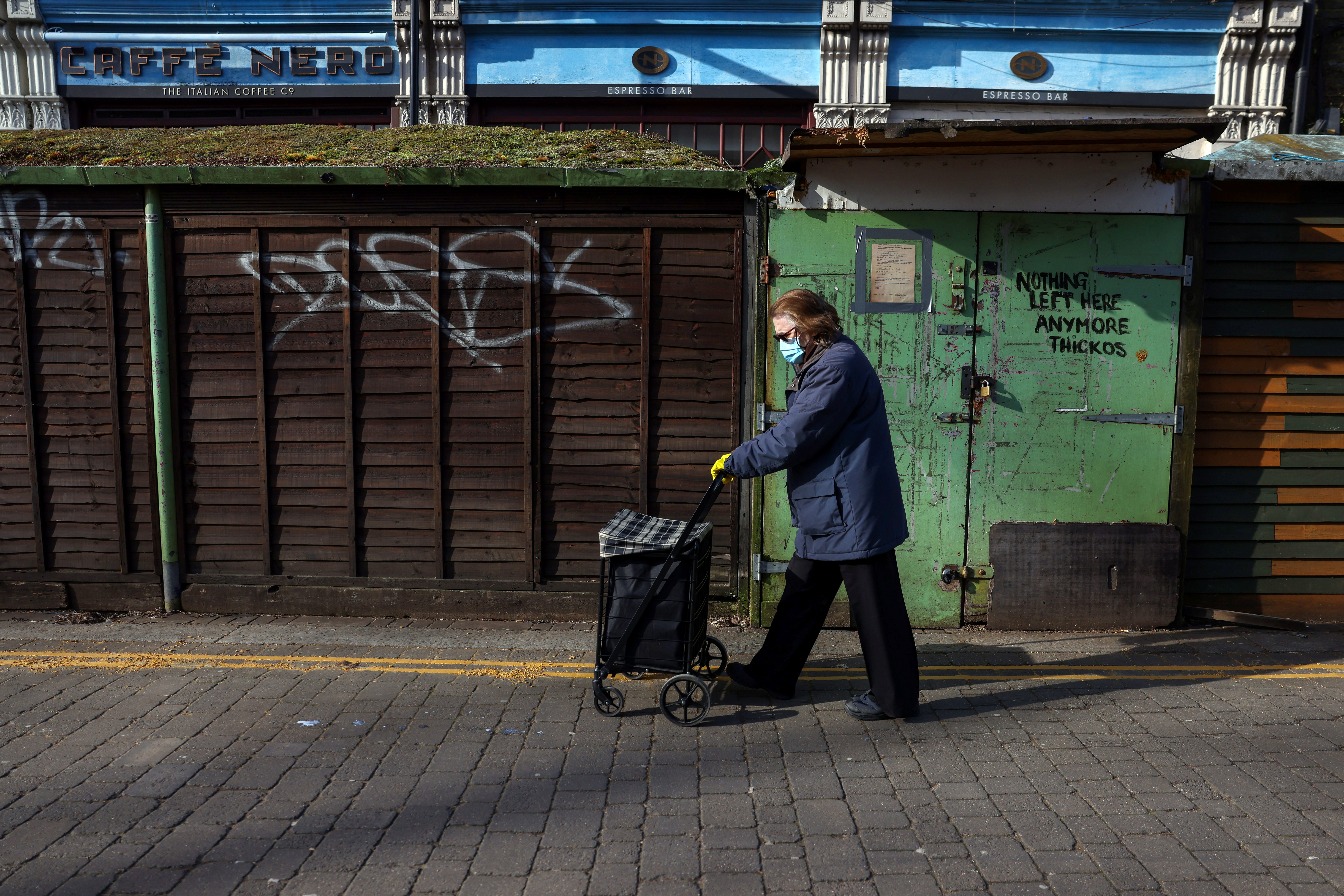 A woman walks past a closed street market as Britain continued its third COVID-19 lockdown in Chiswick, London, Britain, February 13, 2021.   REUTERS/Kevin Coombs