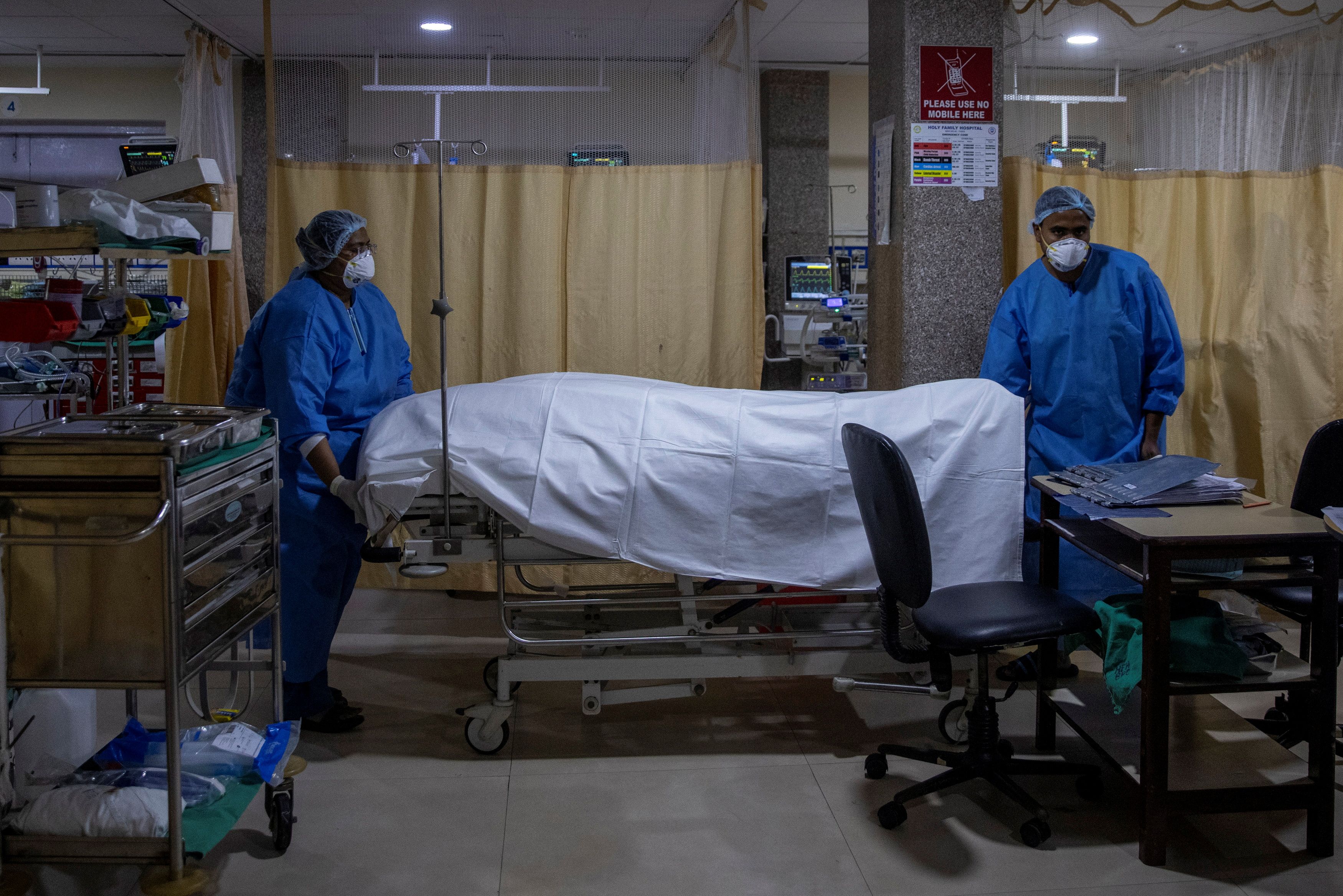 Hospital workers remove the body of a person, who died from the coronavirus disease (COVID-19), from the ICU ward at Holy Family Hospital in New Delhi
