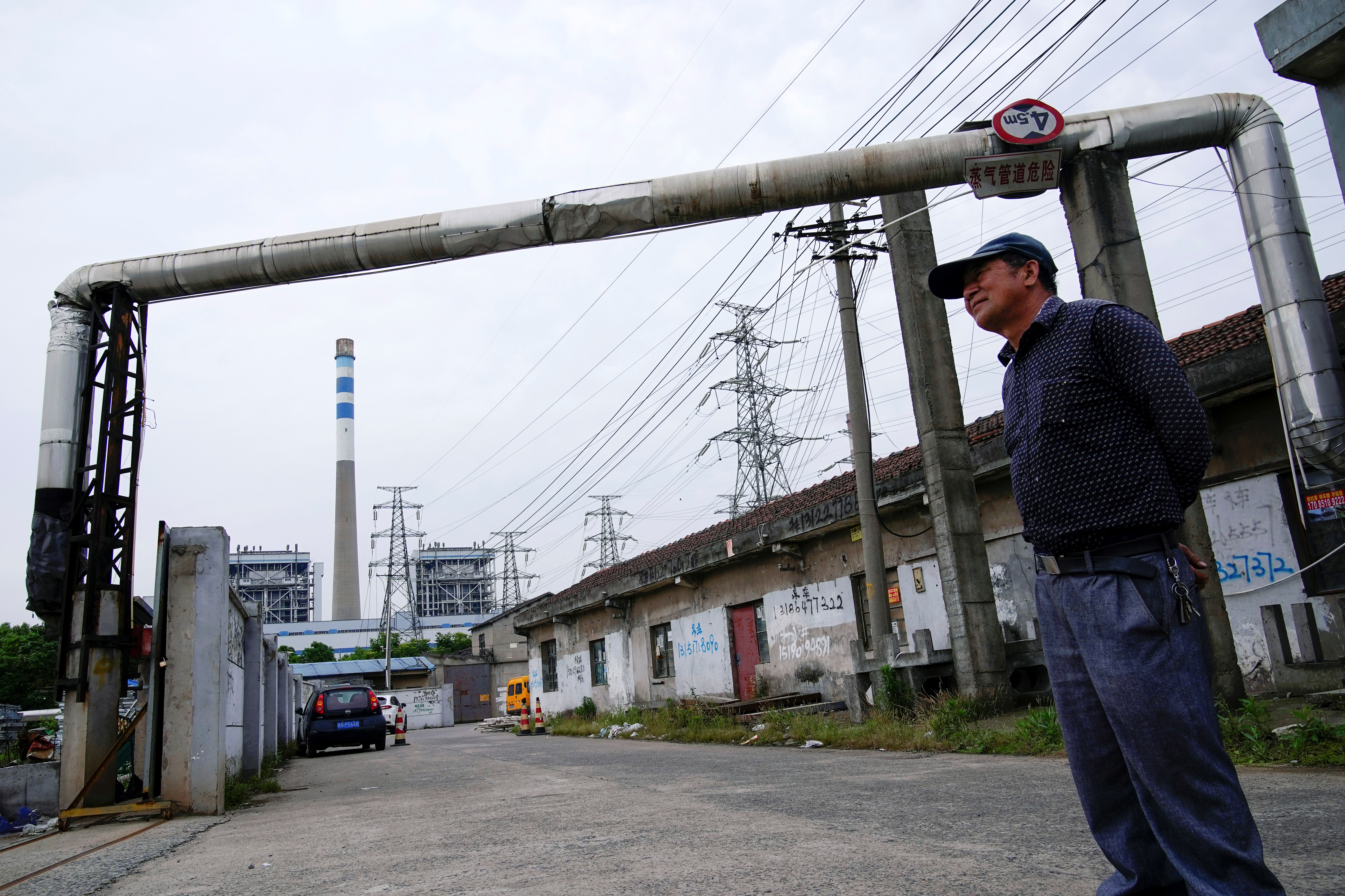 A man stands at a construction site near a coal-fired power plant in Shanghai