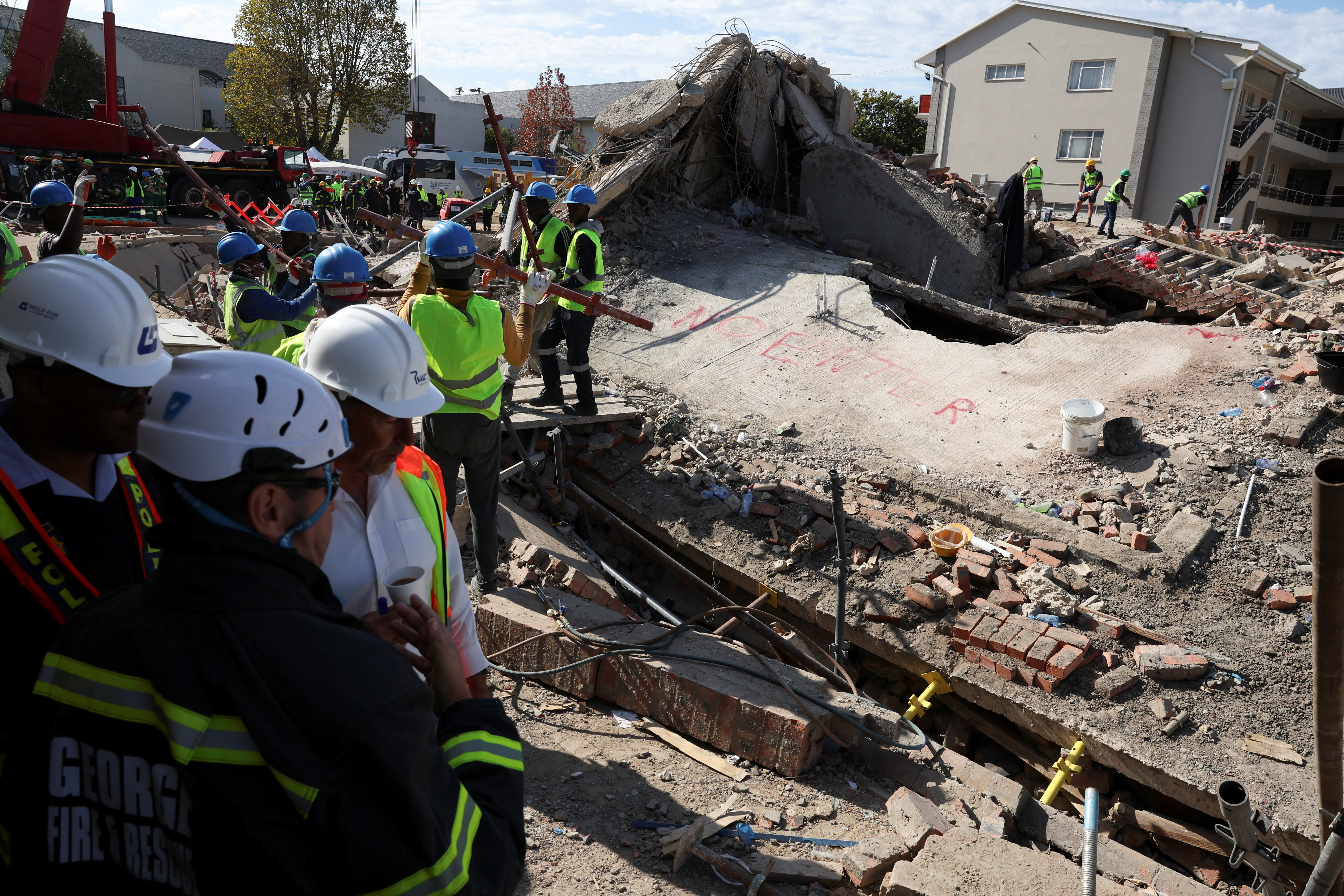 Rescuers work to rescue construction workers trapped under a building that collapsed in George