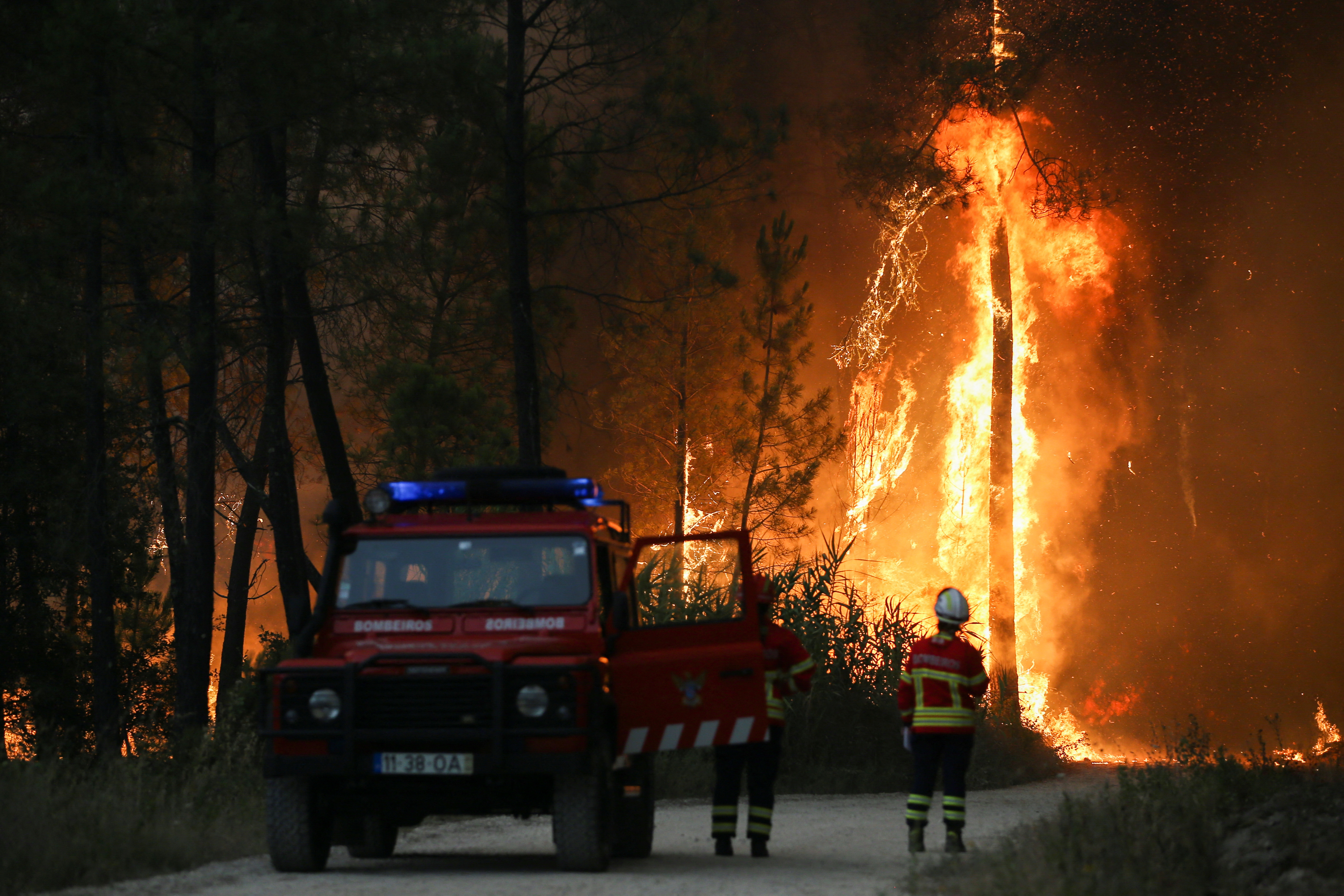 Firefighters watch a wildfire in Ourem