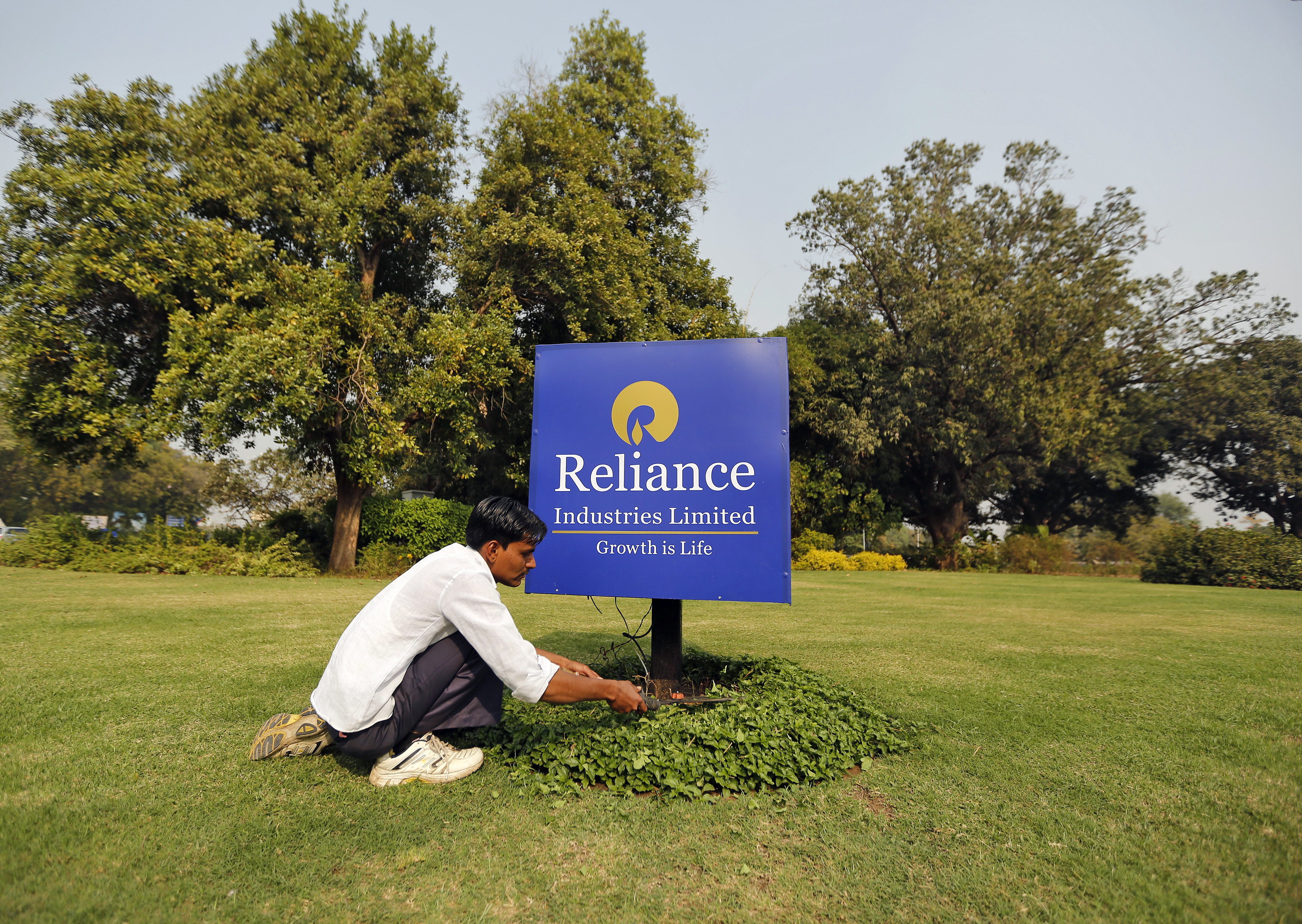 A gardener works next to a board of Reliance Industries Ltd at Gandhinagar in Gujarat