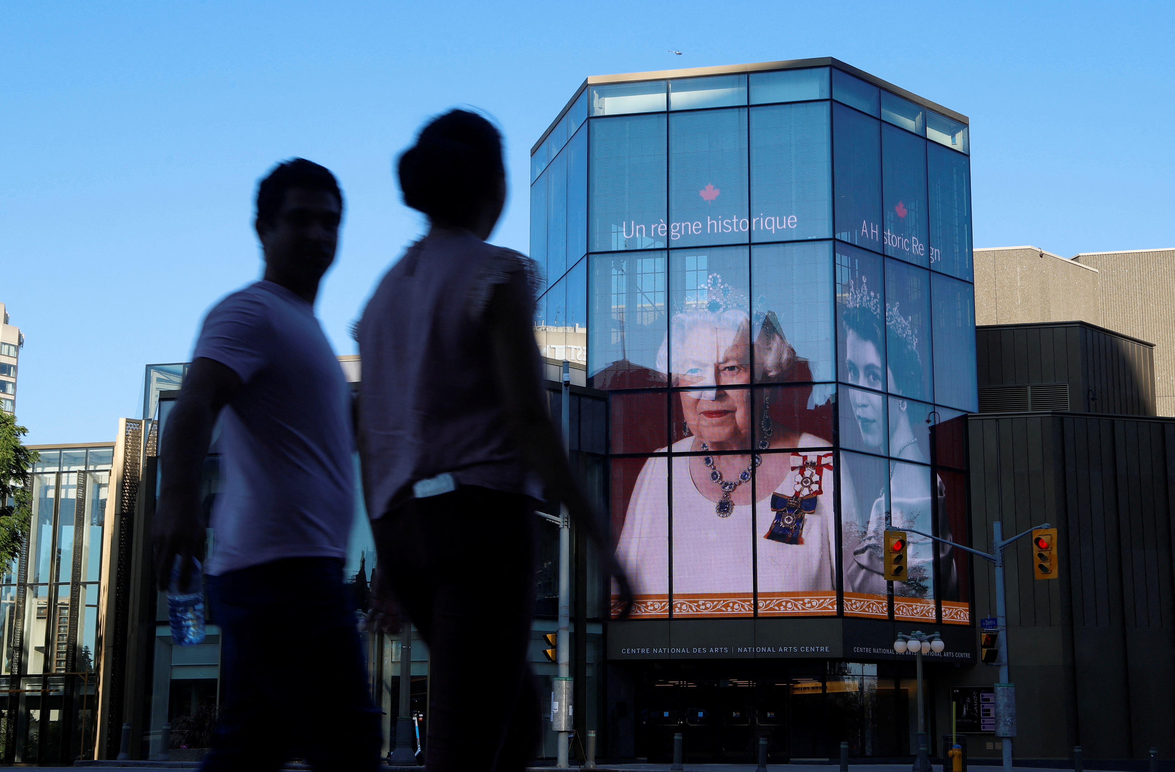 FILE PHOTO:People walk by as a tribute to Queen Elizabeth appears on the National Arts Centre, after Queen Elizabeth's passing, in Ottawa
