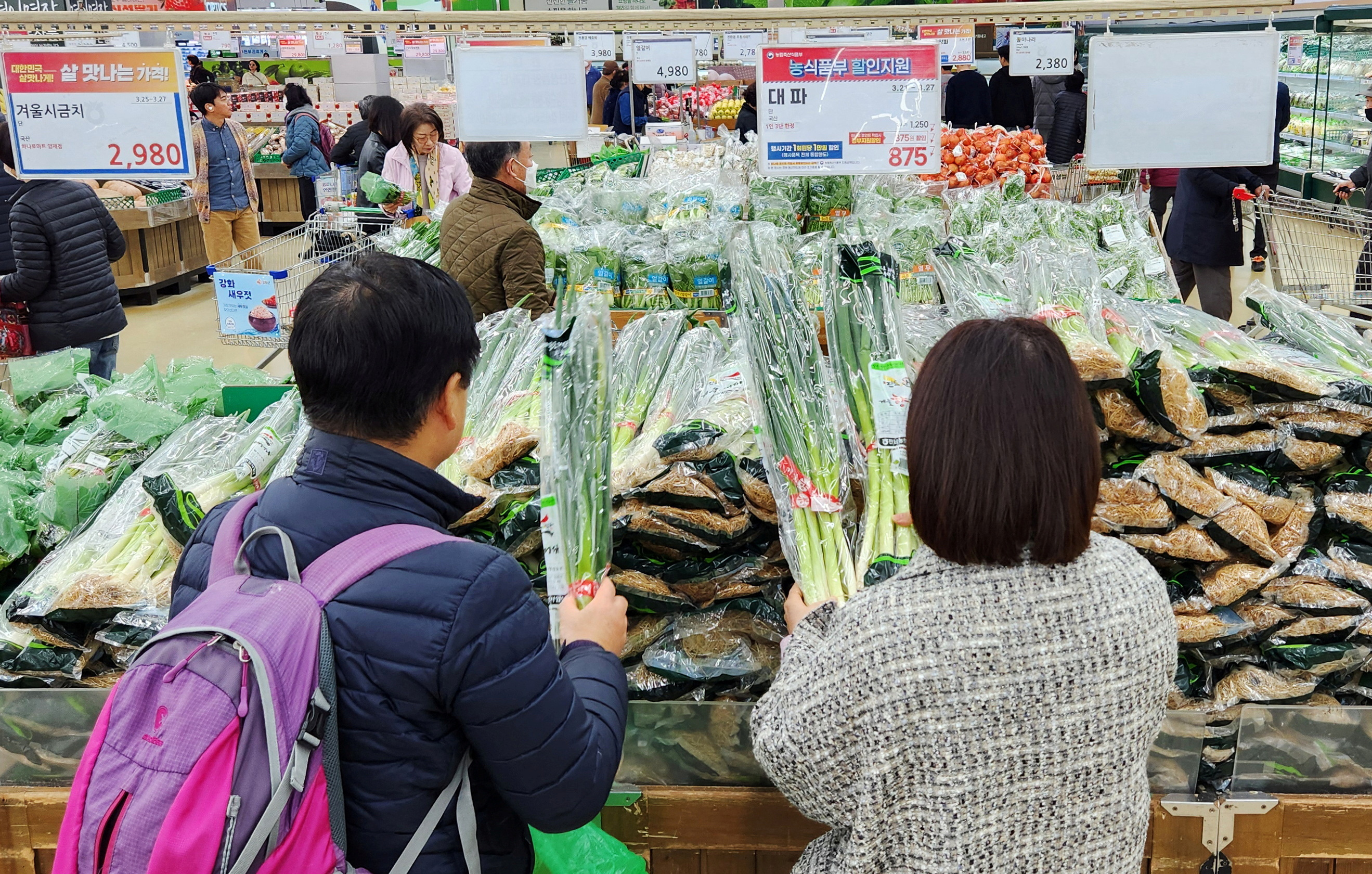 Women shop for green onions at a market in Seoul