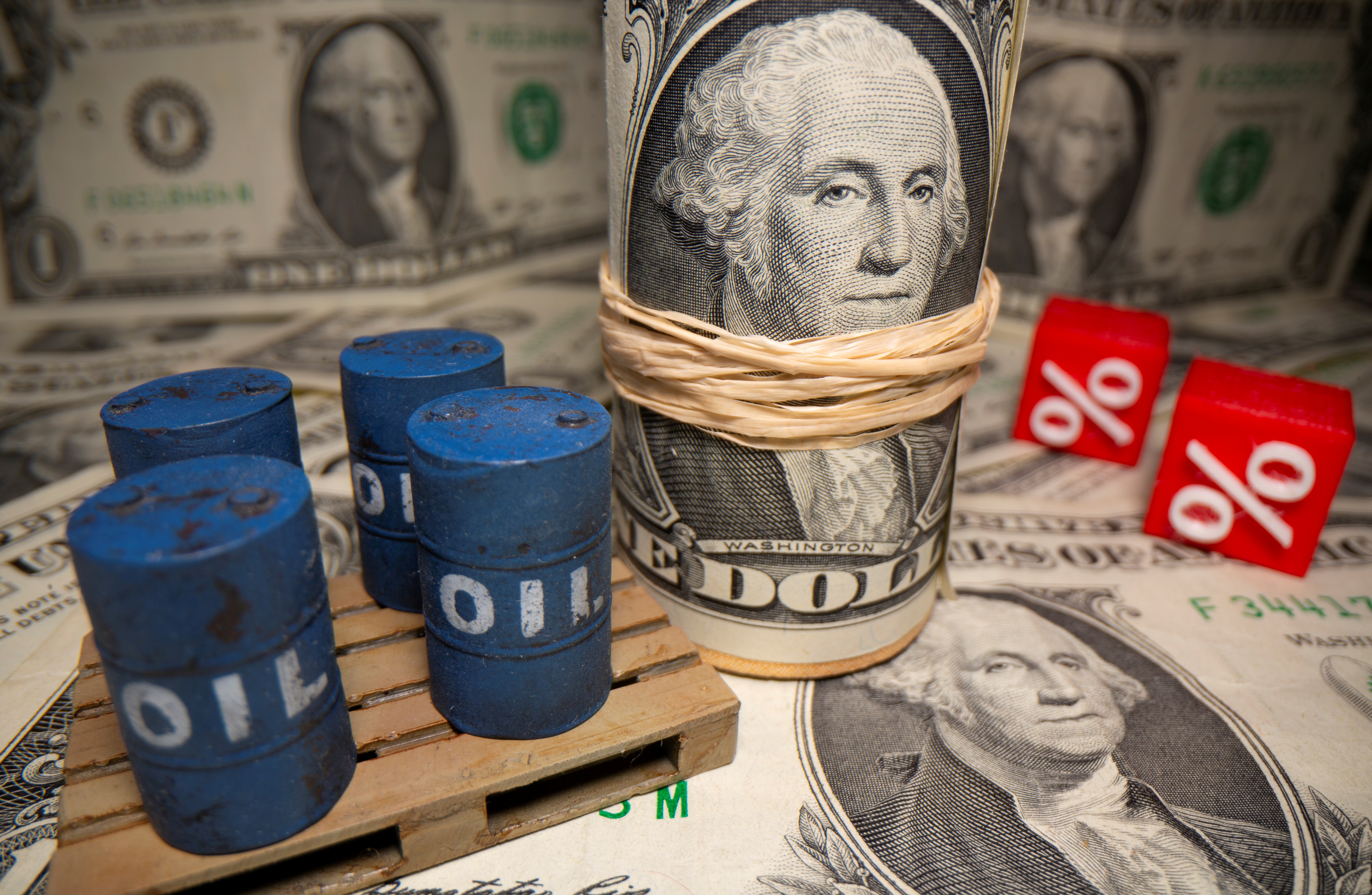 3D printed oil barrels and percentage symbols are seen in front of dollar banknotes in this illustration