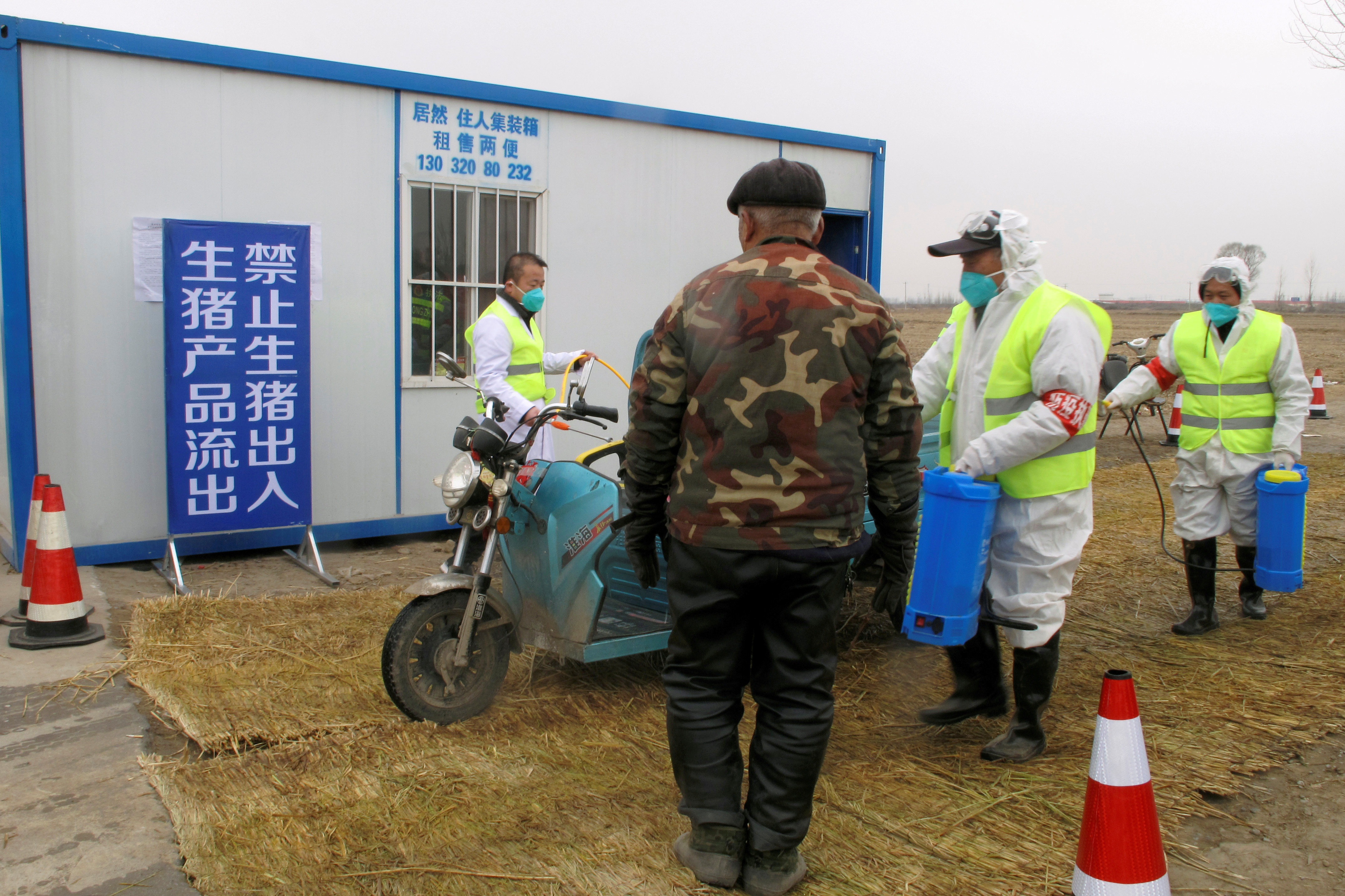 Workers disinfect a vehicle at a checkpoint on a road leading to a farm where African swine fever was detected in Xushui