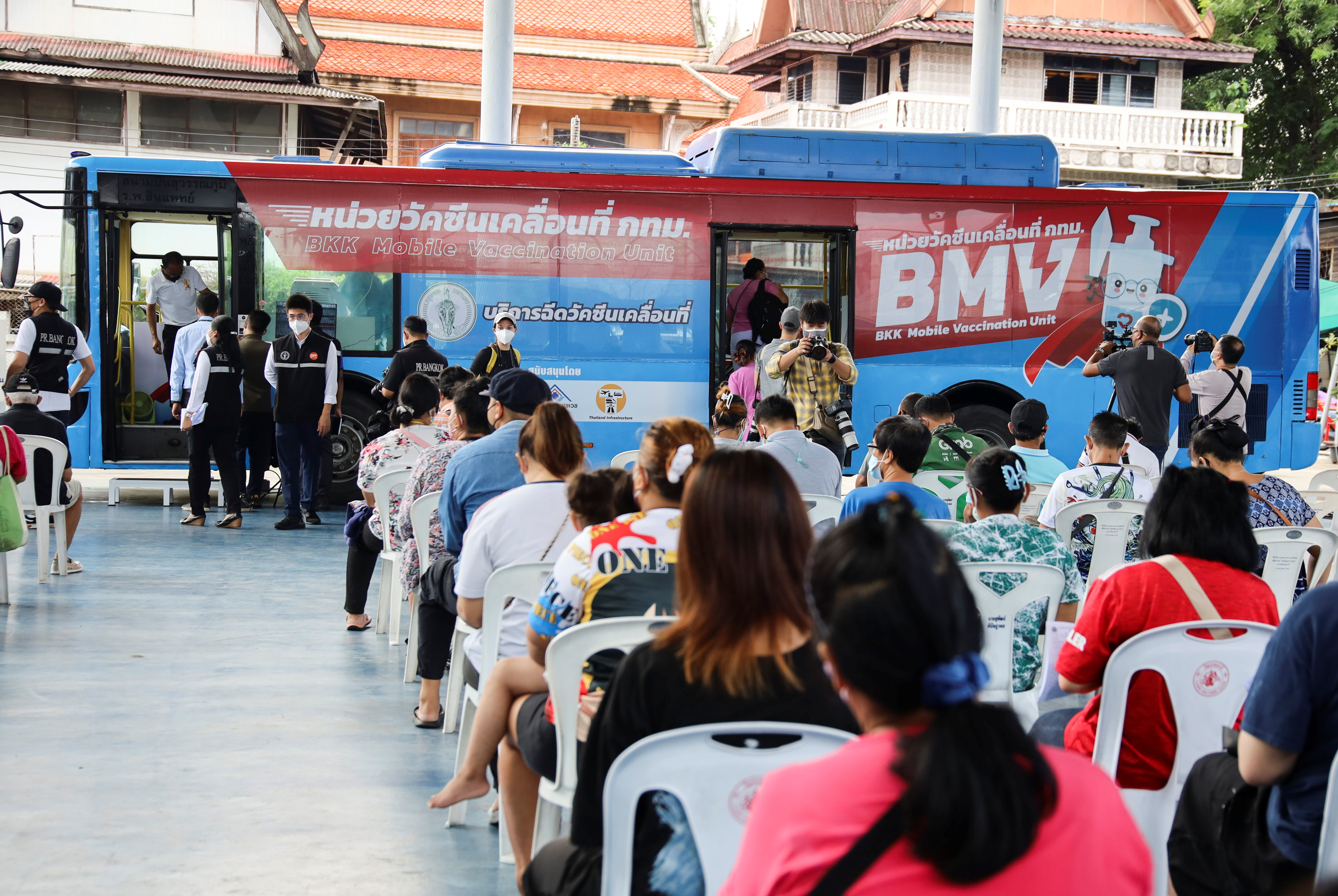 People wait in front of a coronavirus disease (COVID-19) mobile vaccination bus set-up to serve the elderly and disabled groups in Bangkok