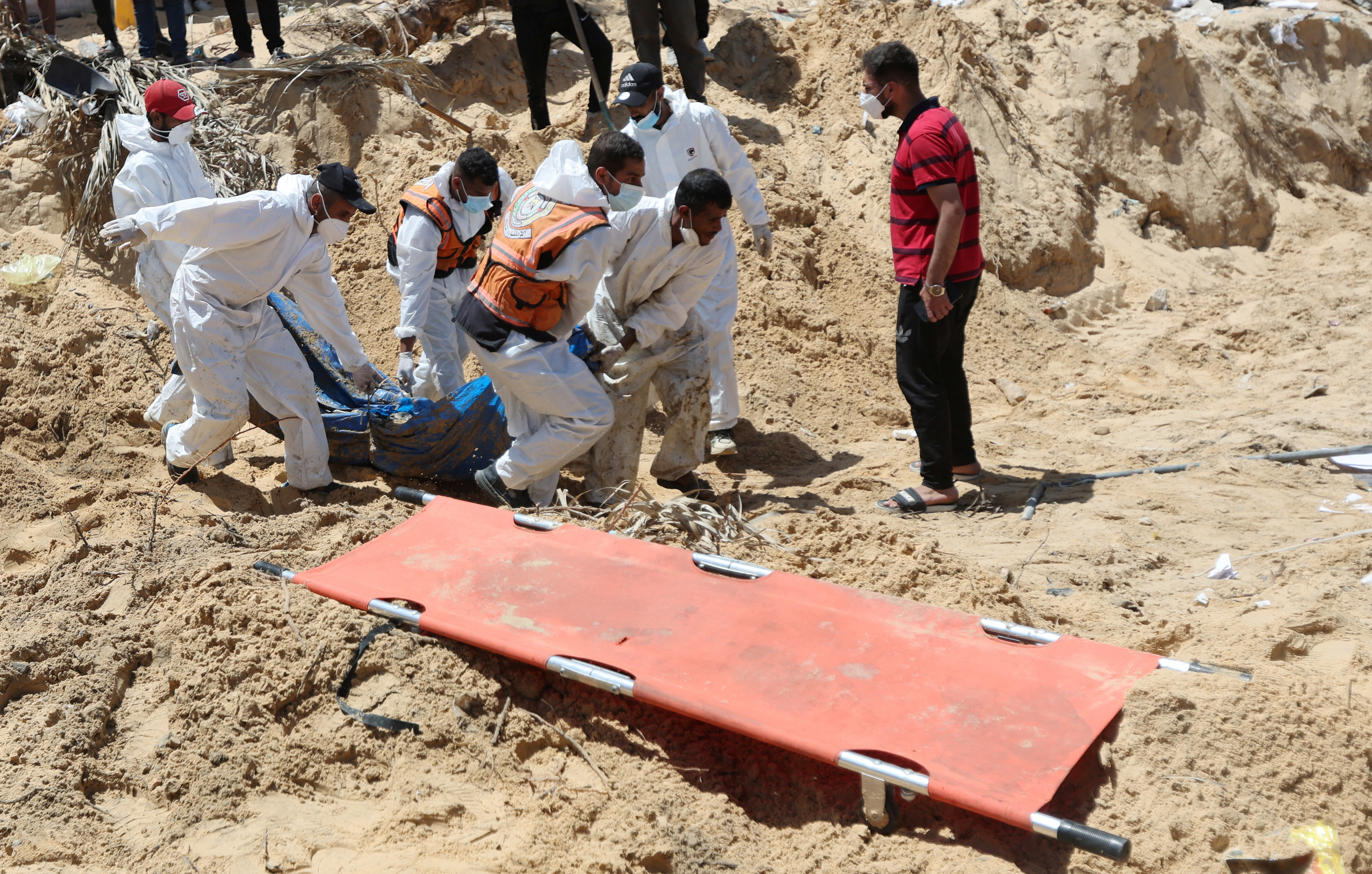 People work to move into a cemetery bodies of Palestinians killed during Israel's military offensive and buried at Nasser hospital, in Khan Younis