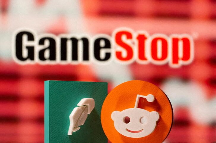 3d printed Robinhood and Reddit logos are seen in front of displayed GameStop logo